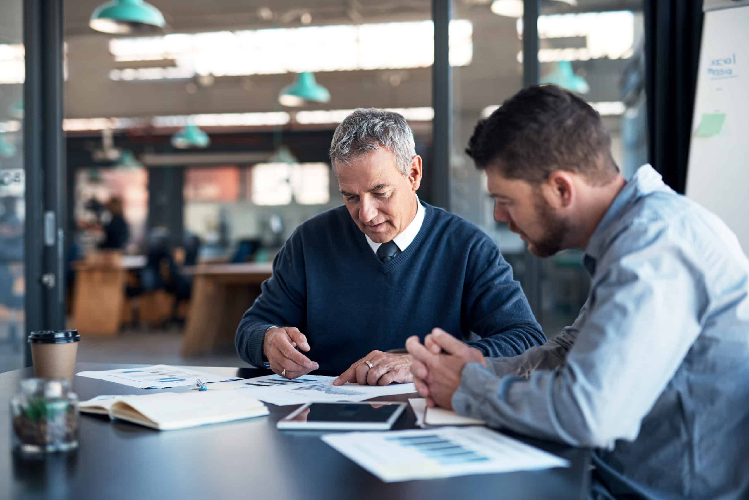 Two men discussing predictive maintenance consulting at a table in a modern office setting.