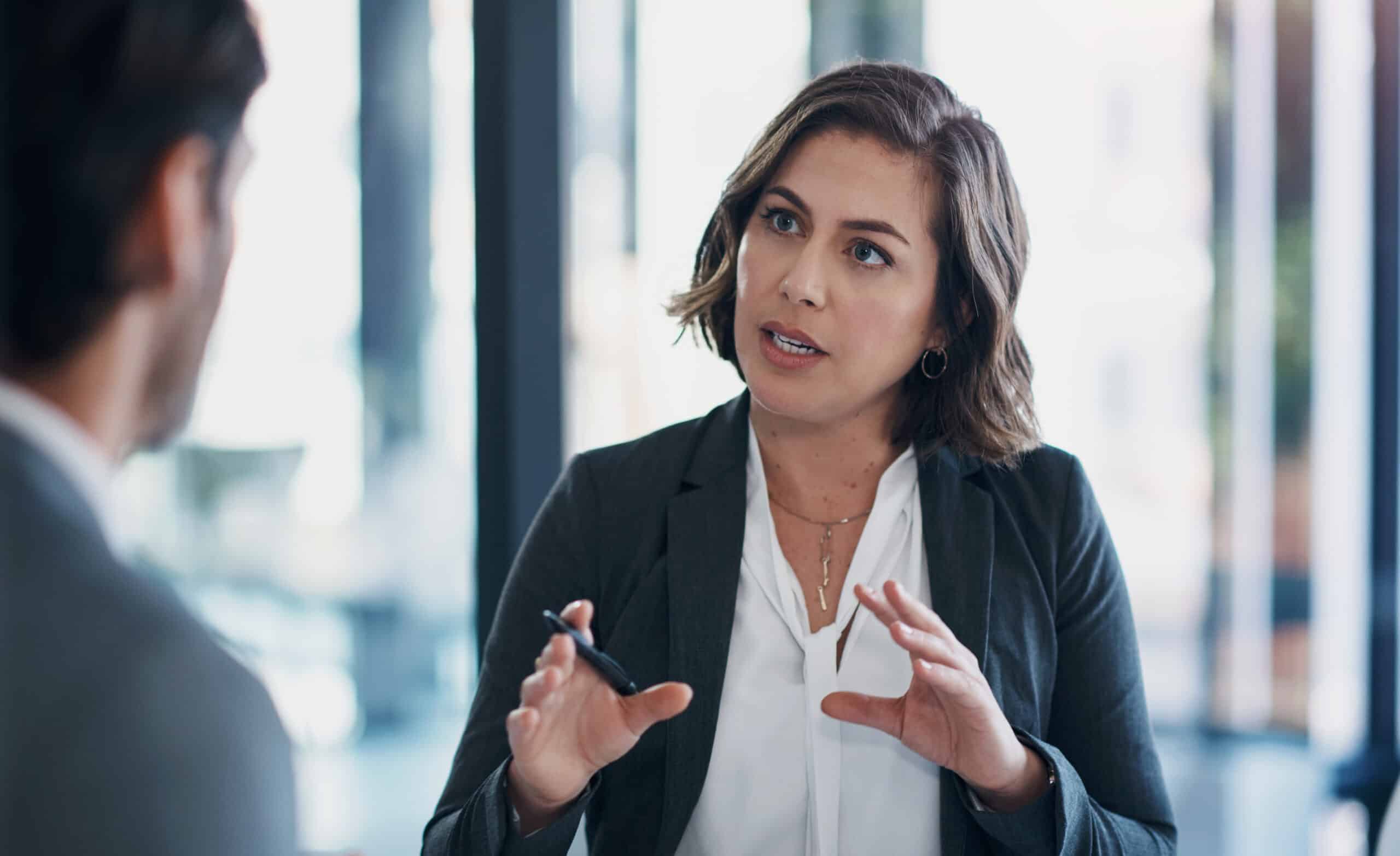 Woman in business attire discusses predictive maintenance consulting with a colleague in the office.