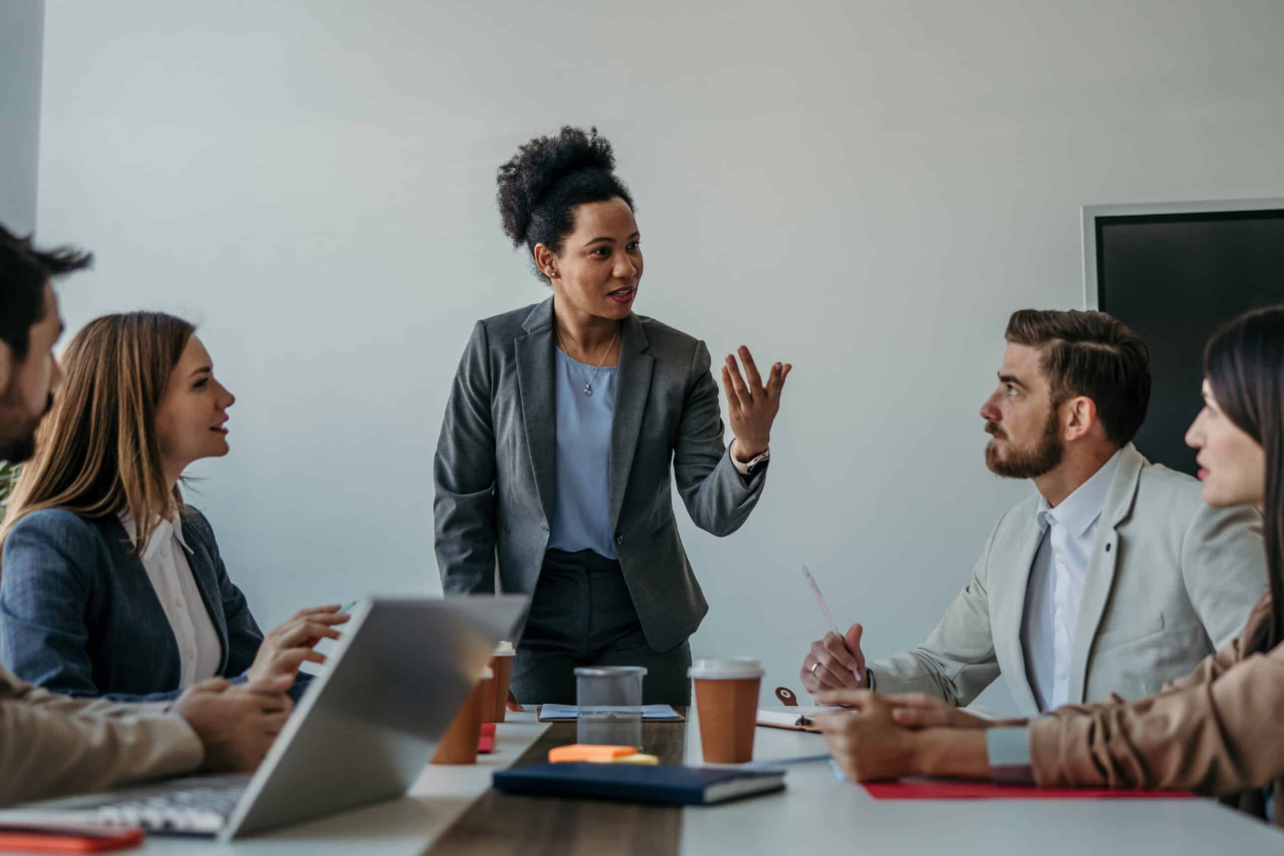 Woman leading a proptech strategy meeting with four colleagues around a conference table.
