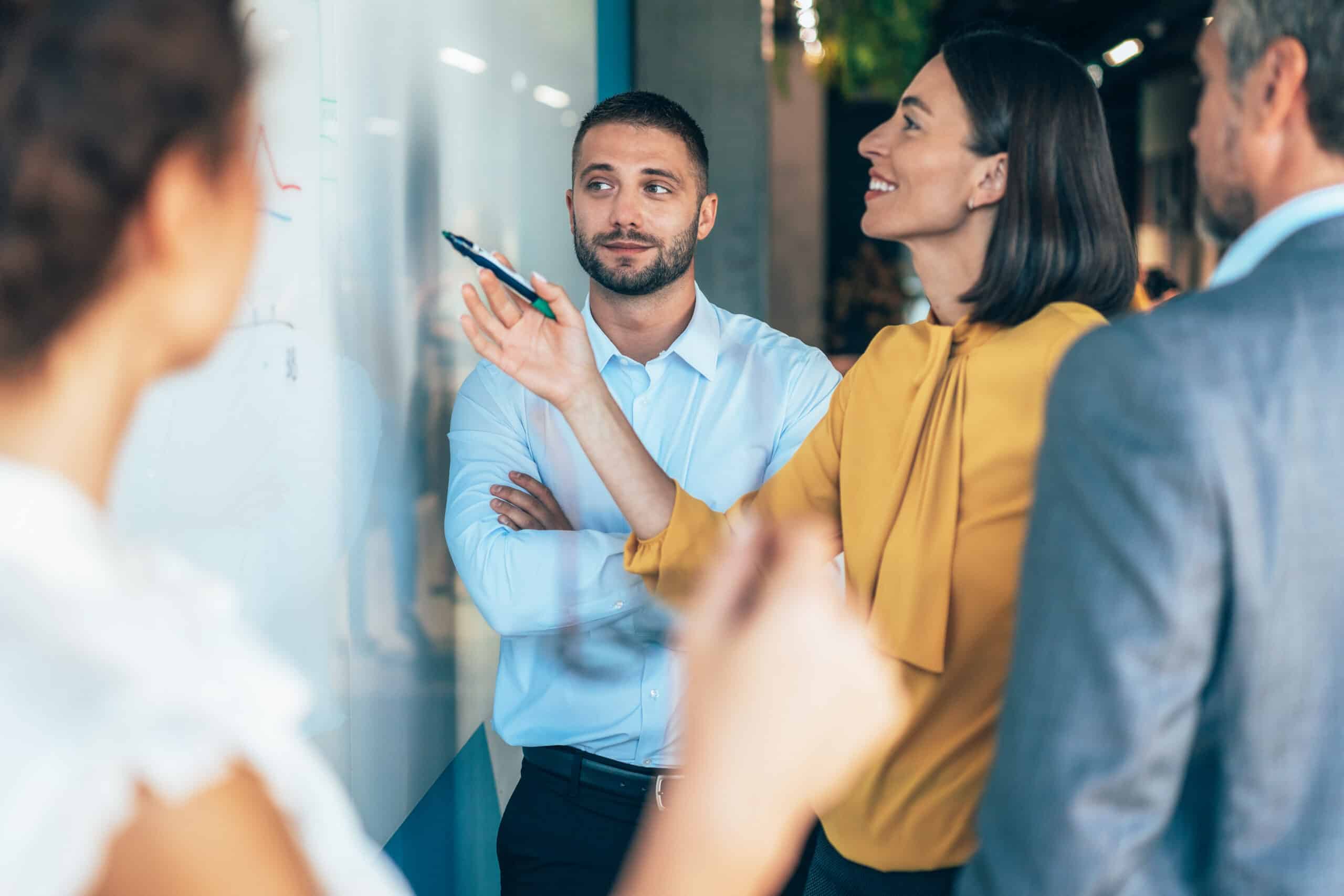 Four people discuss real estate fair market value analysis at a whiteboard; one woman smiles.