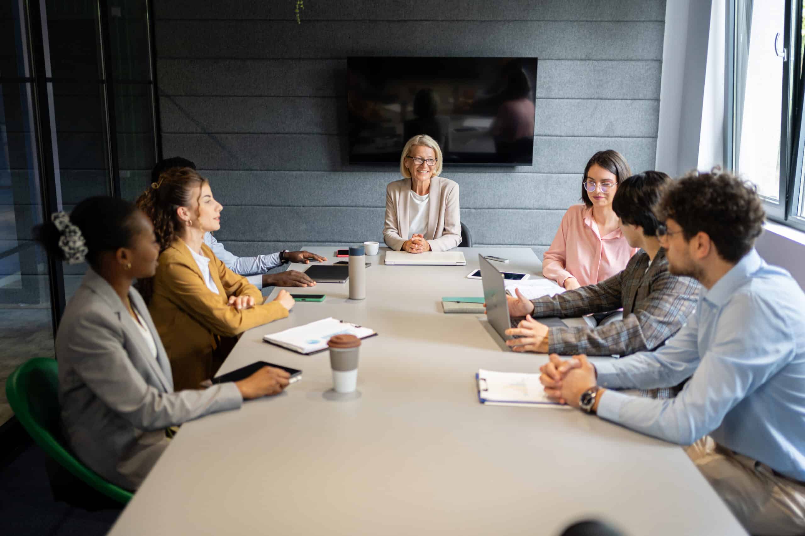 Eight people in a meeting room discuss real estate fair market value analysis consulting.