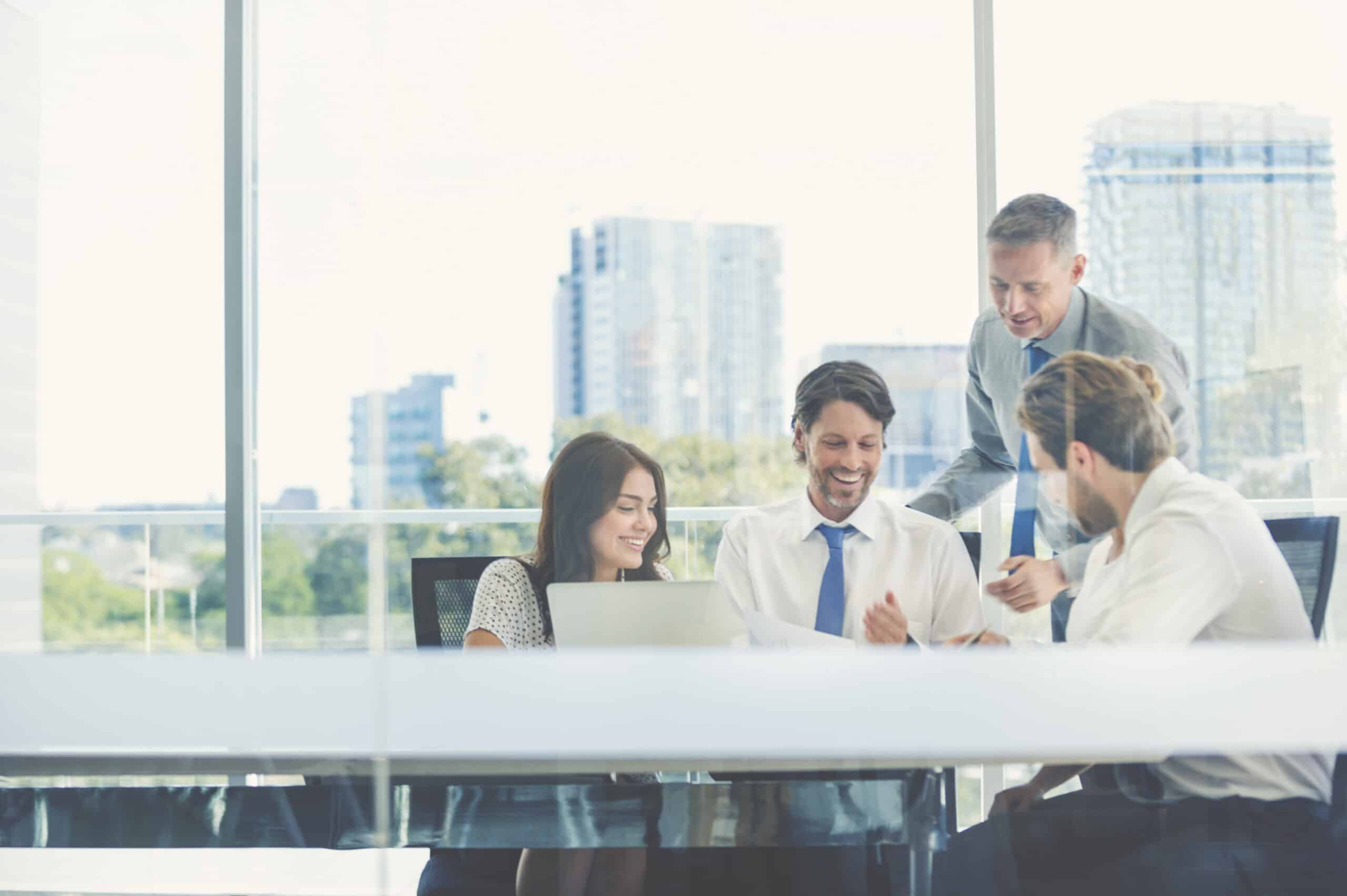 Four smart building consultants collaborate around a laptop in a bright office.