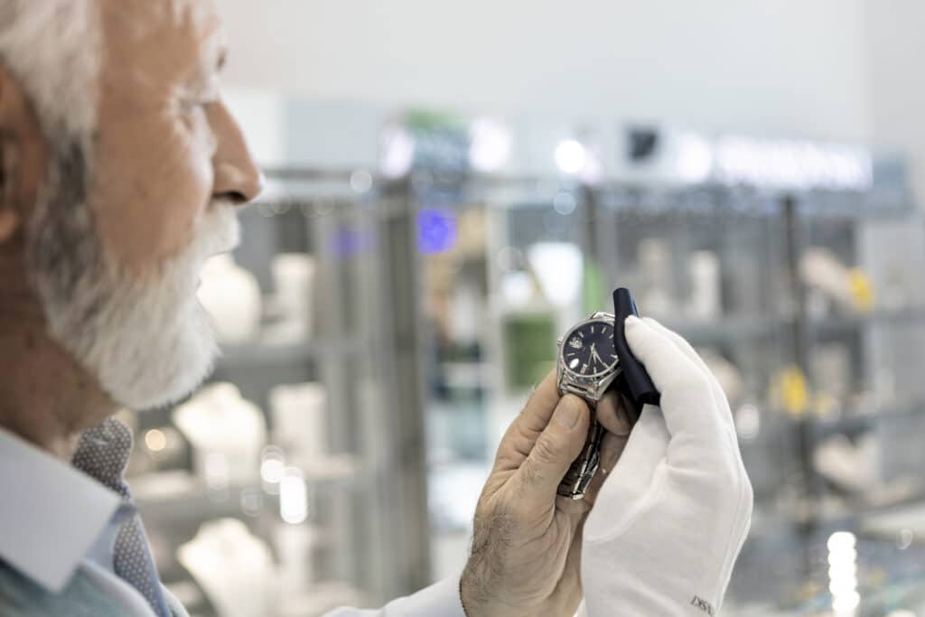 Senior man in jewelry store selling luxury watches.