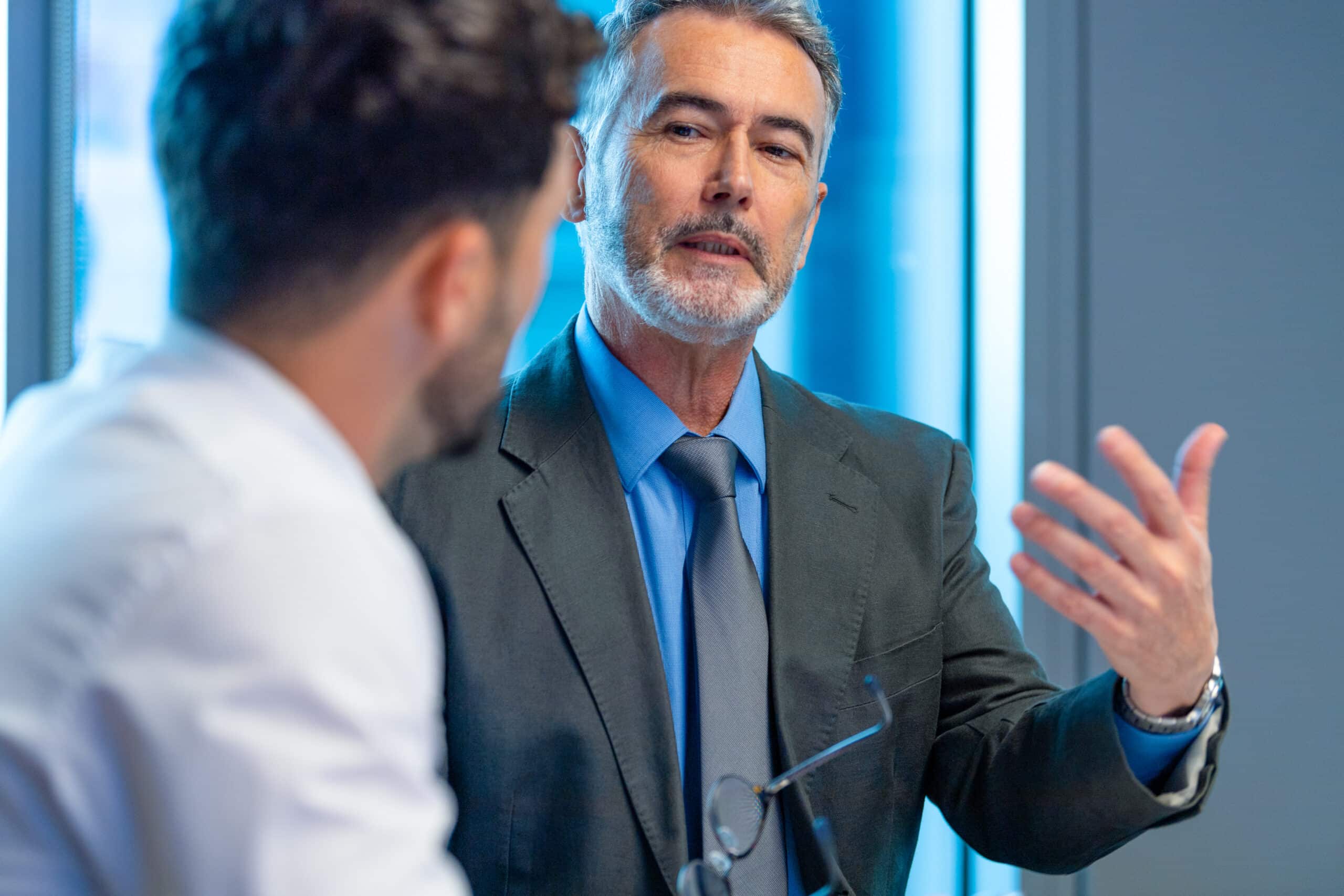 Two men in suits discussing proptech consulting strategies in a modern office setting.