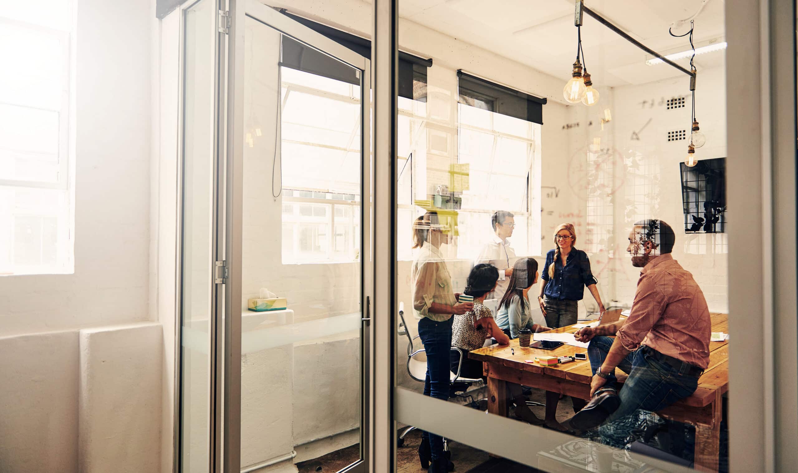 Team discusses CRE Change Management in a modern office conference room with glass walls.