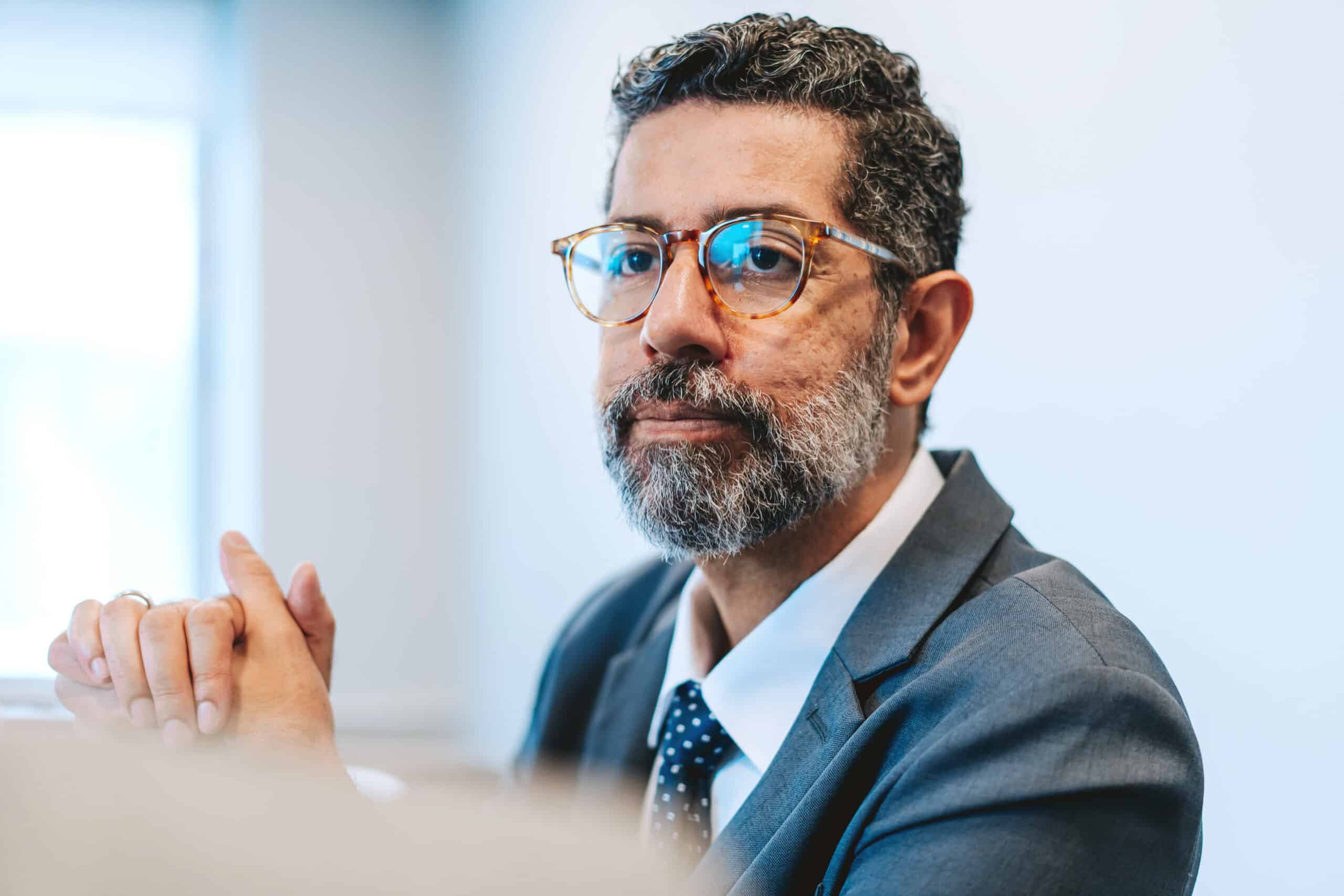 Man with glasses and beard in suit, reflecting on a Real Estate Fair Market Value Analysis.