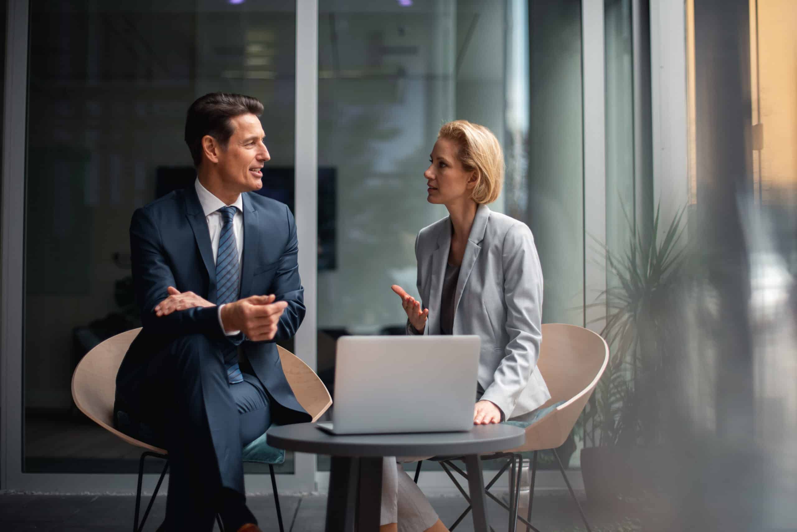 Two business professionals discuss Land Use Planning Consulting at a table in a modern office.