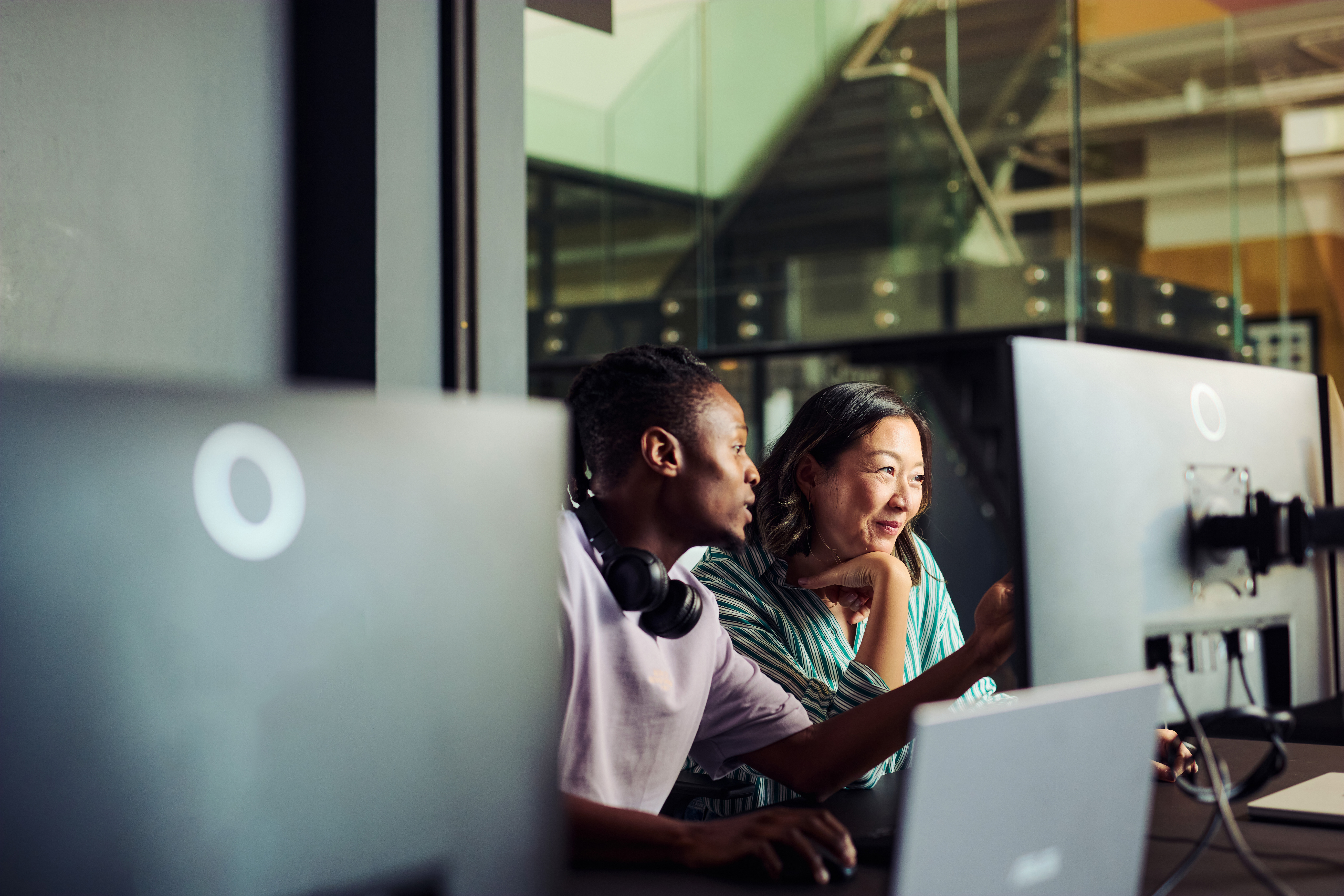 Two people discuss cloud migration consulting at a computer in a modern office setting.