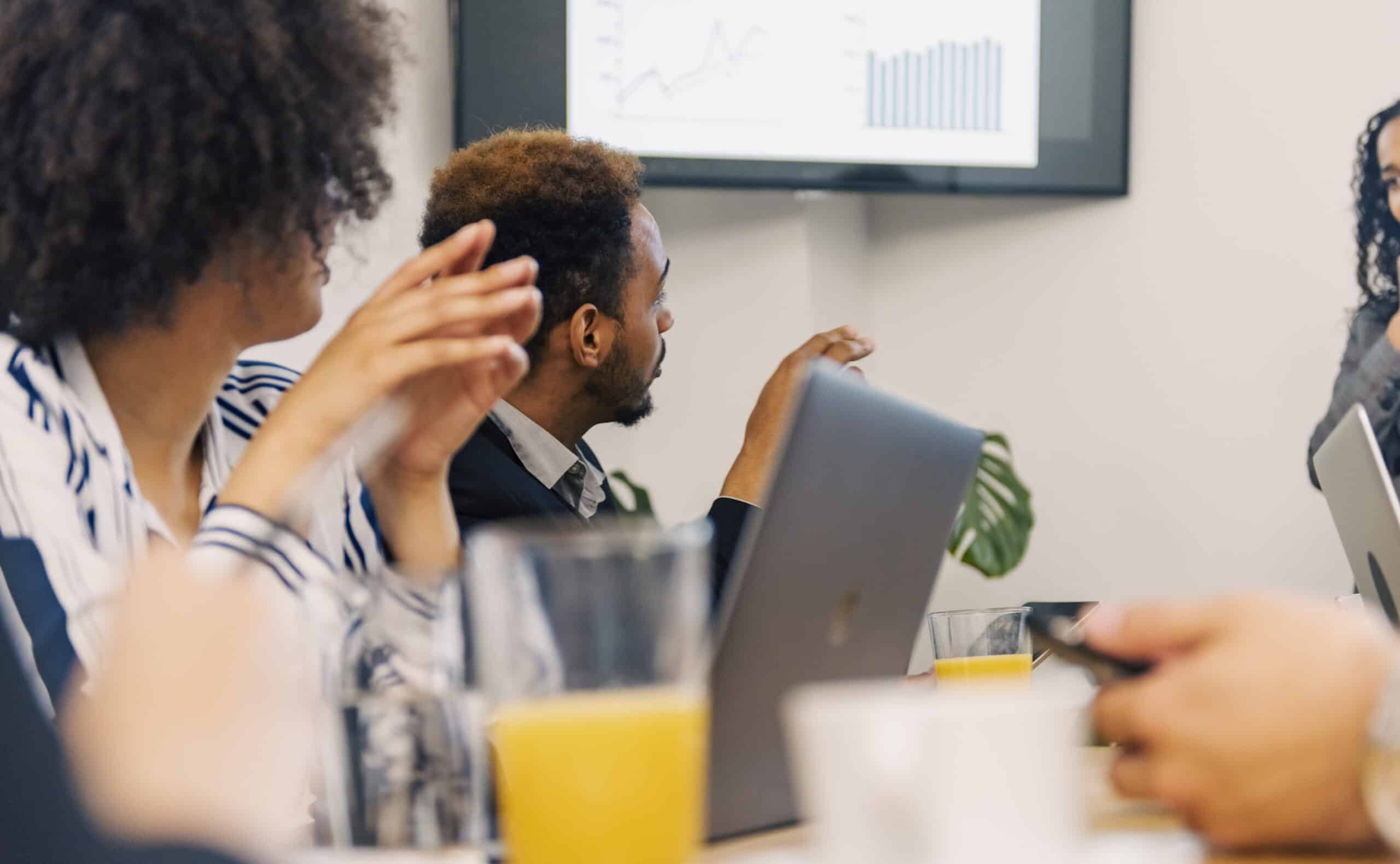 People in a meeting room with laptops, discussing charts and graphs on Digital Twins.