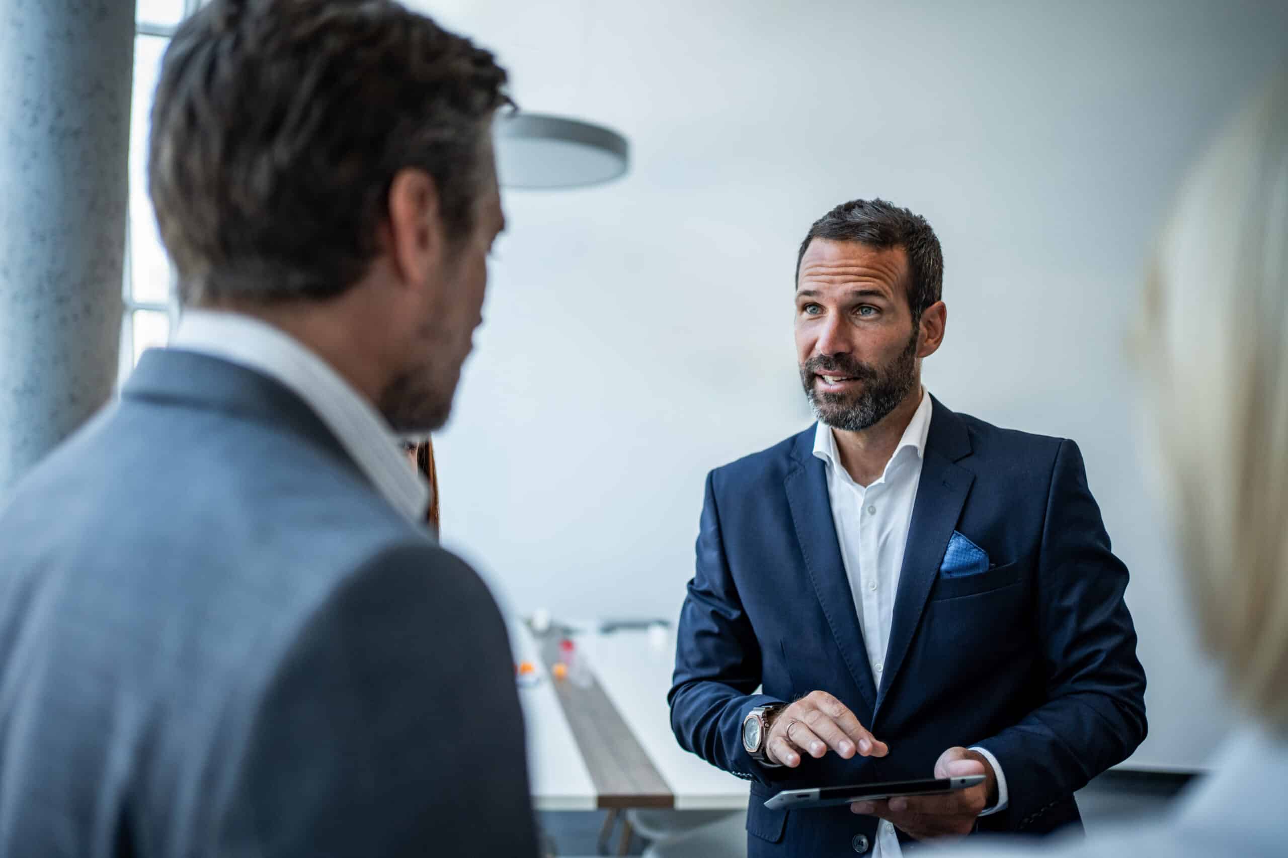 Man in a suit discusses Location Intelligence insights with colleagues in a modern office setting.