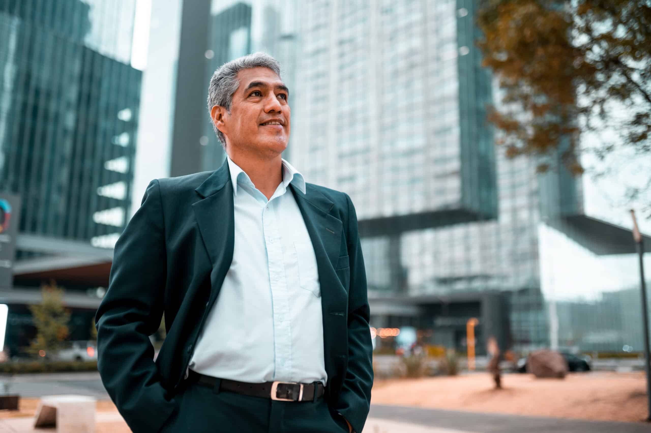 Confident man in suit stands outdoors, embodying CRE Change Management amid glass buildings.