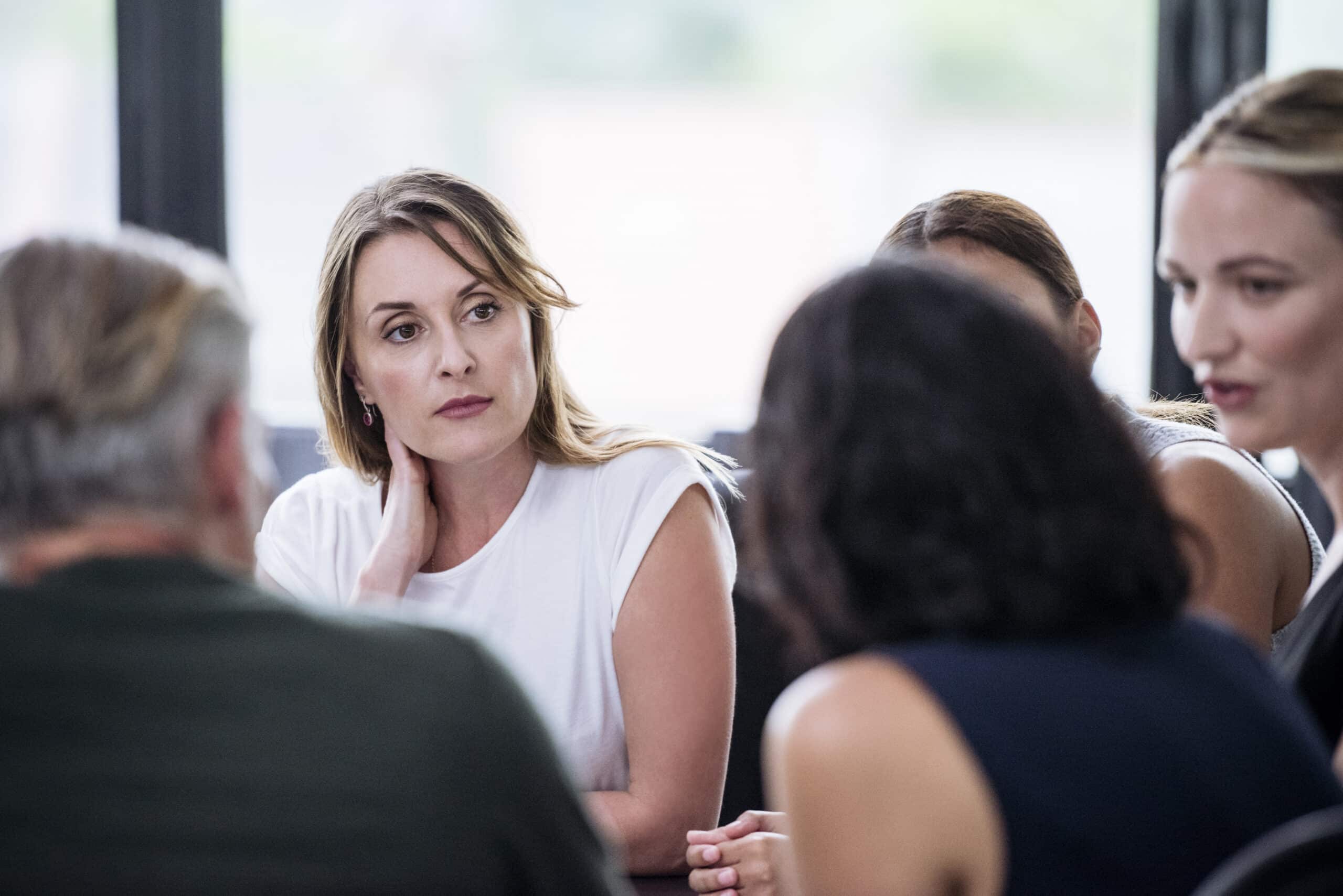 A woman listens thoughtfully during a Digital Experience Platform consulting meeting at a table.