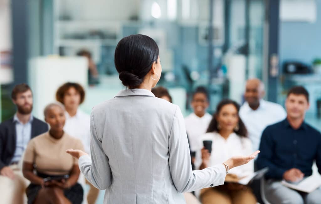 A woman speaks to a group about commercial real estate change management consulting