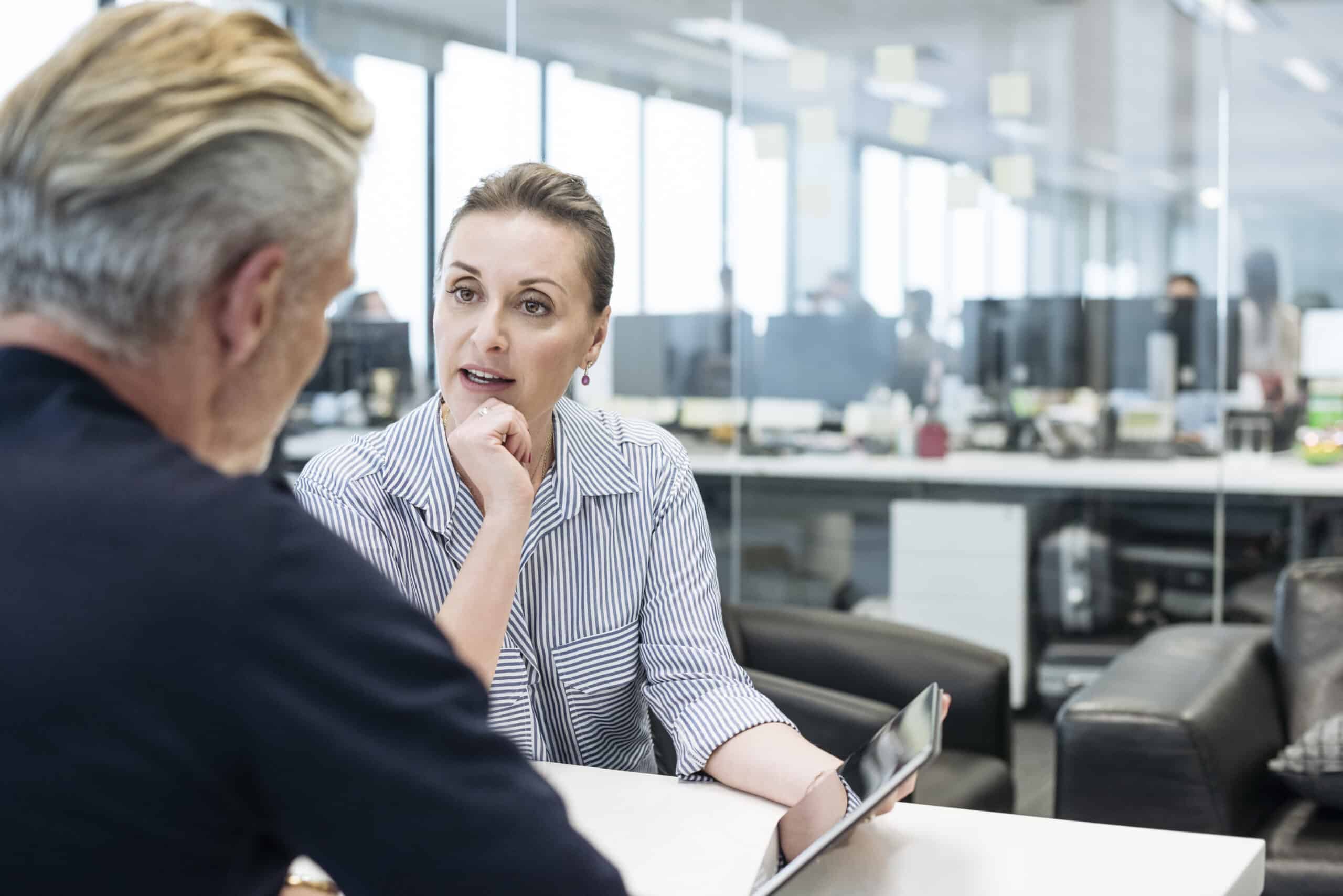 Two people having a serious IT Governance discussion at a table in a modern office setting.