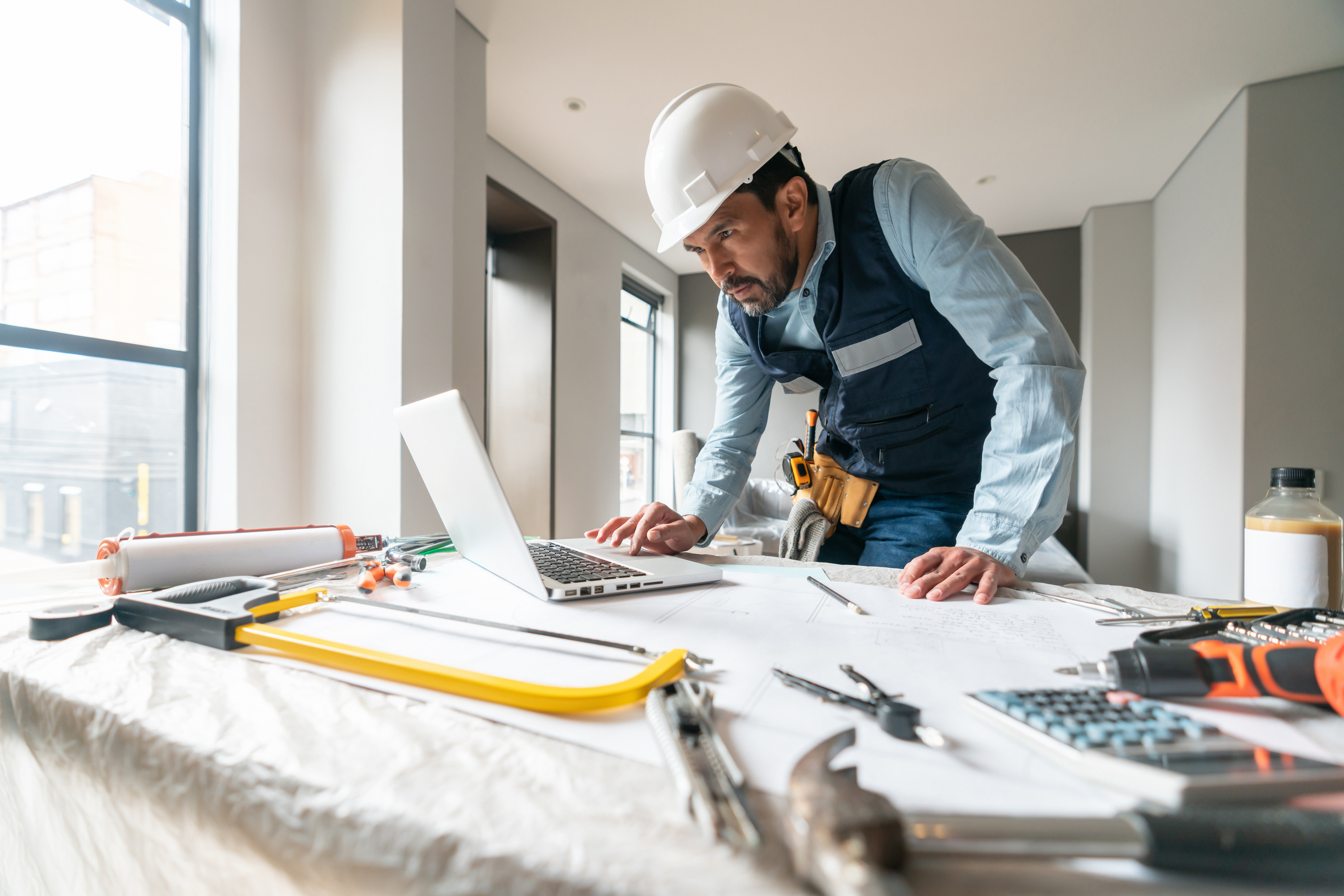 Building contractor working in a house renovation and using his laptop