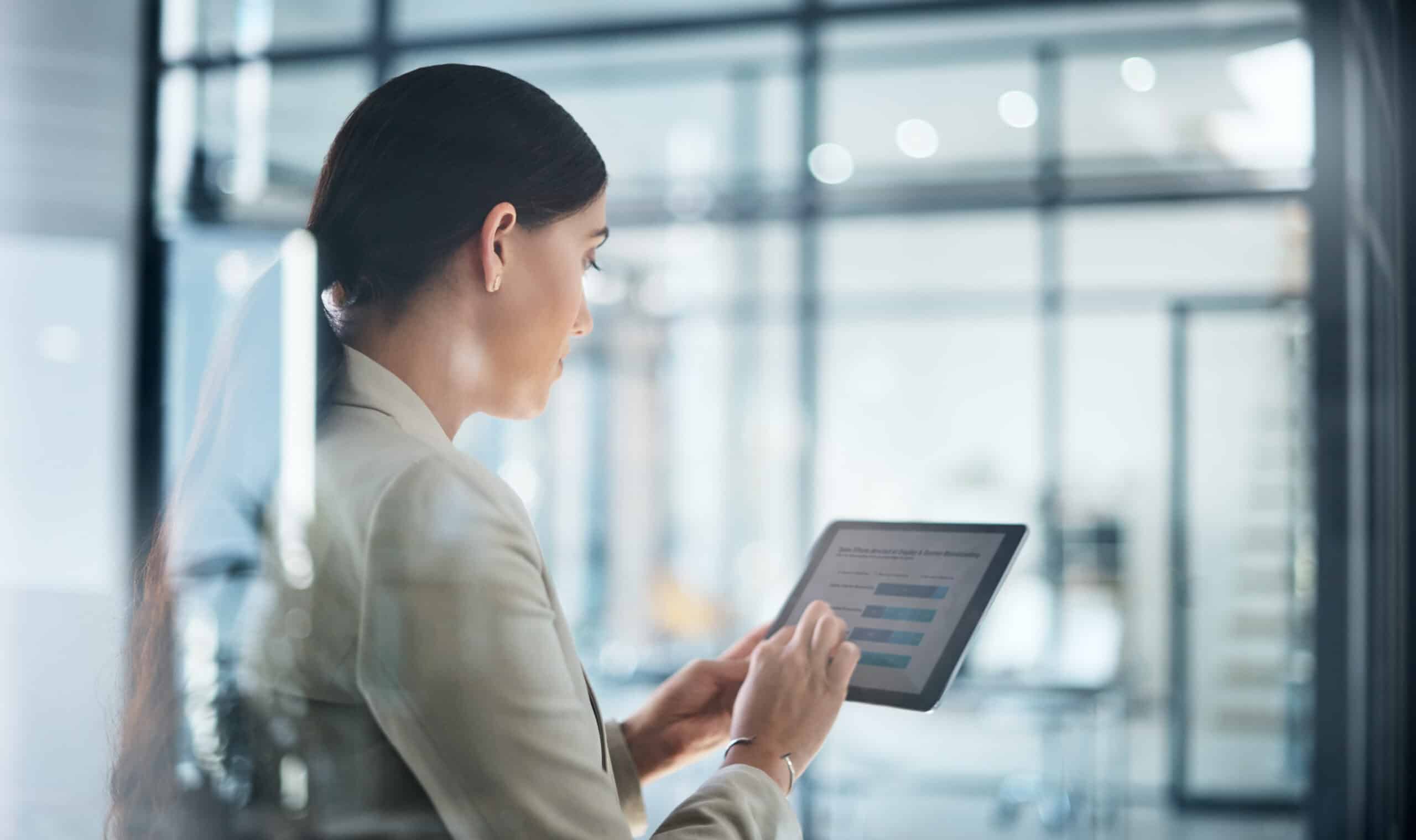 Businesswoman using a tablet with Digital Experience Platform graphs in a modern office setting.