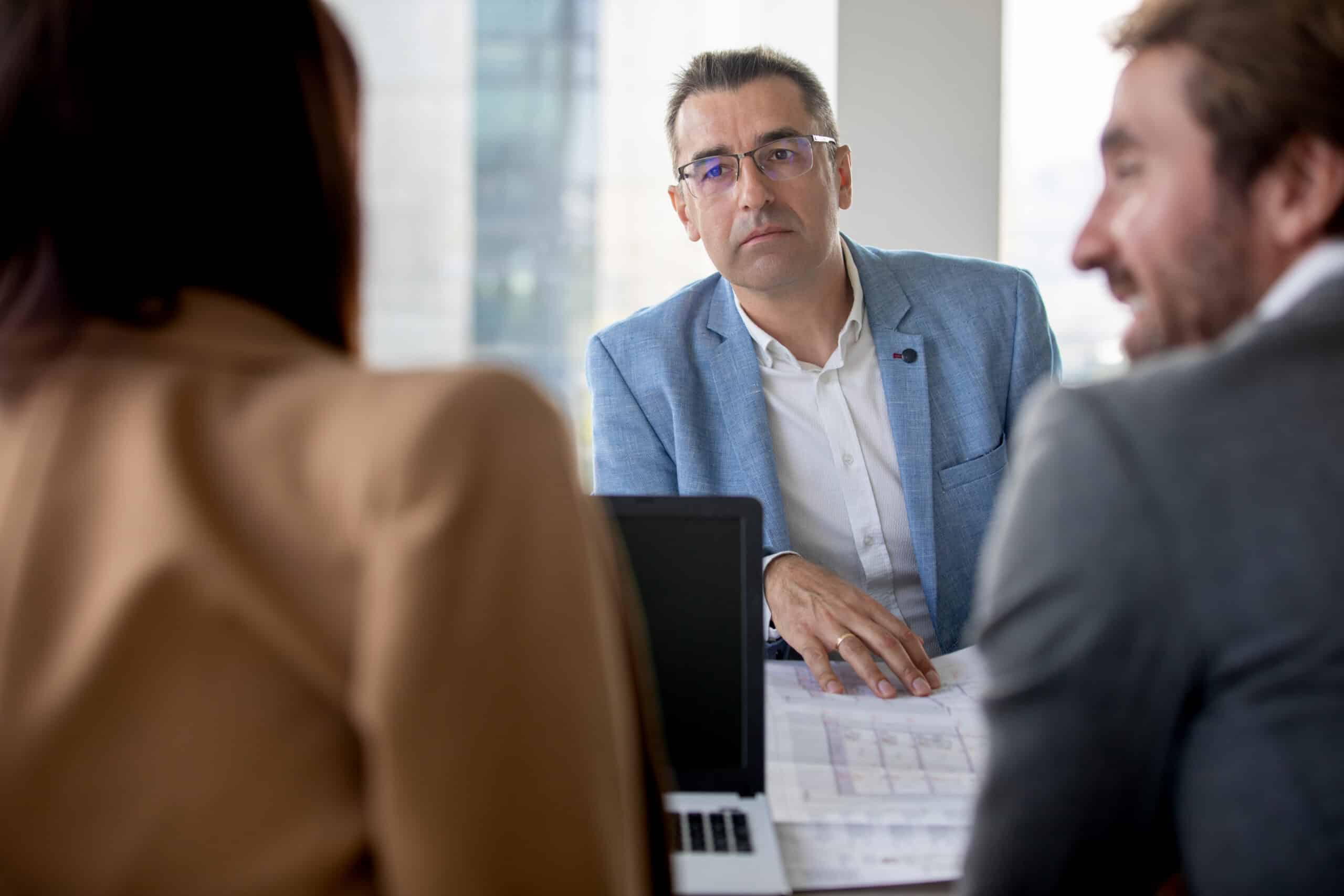Three professionals in a meeting, focusing on Commercial Lease Dispute Resolution​ Consulting.