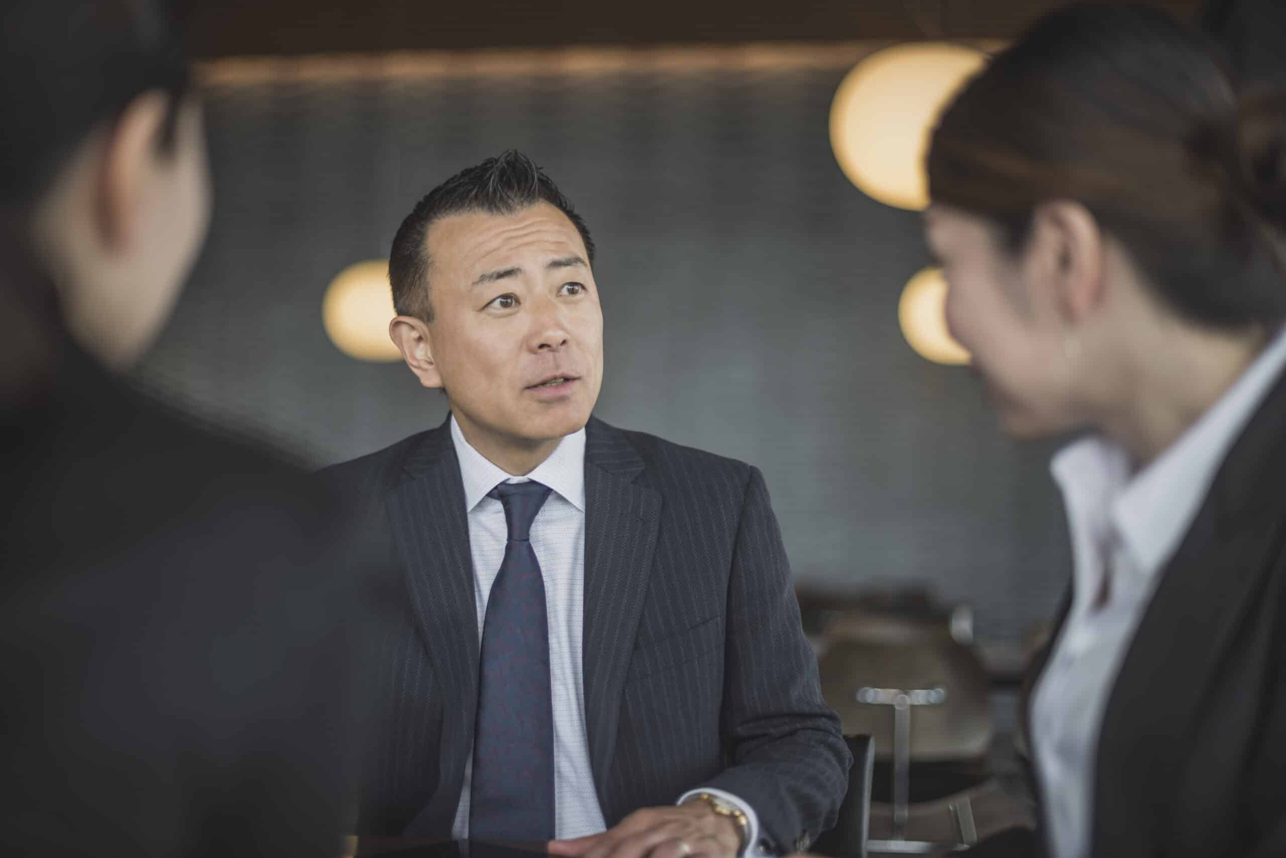 Man in suit discusses strategy with colleagues, aided by Location Intelligence insights.