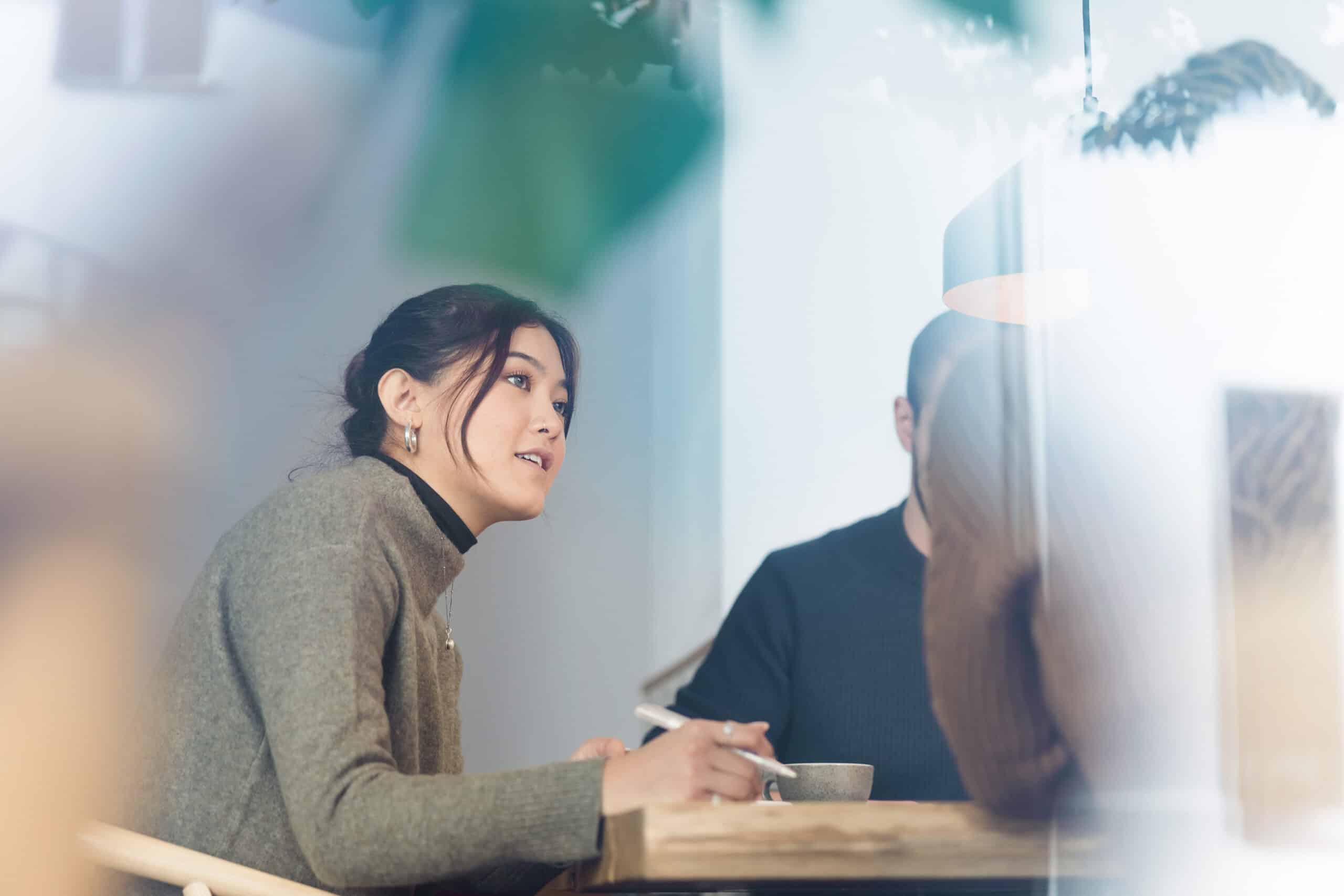 Woman holding a pen, discussing digital experience platform consulting in a softly lit room.