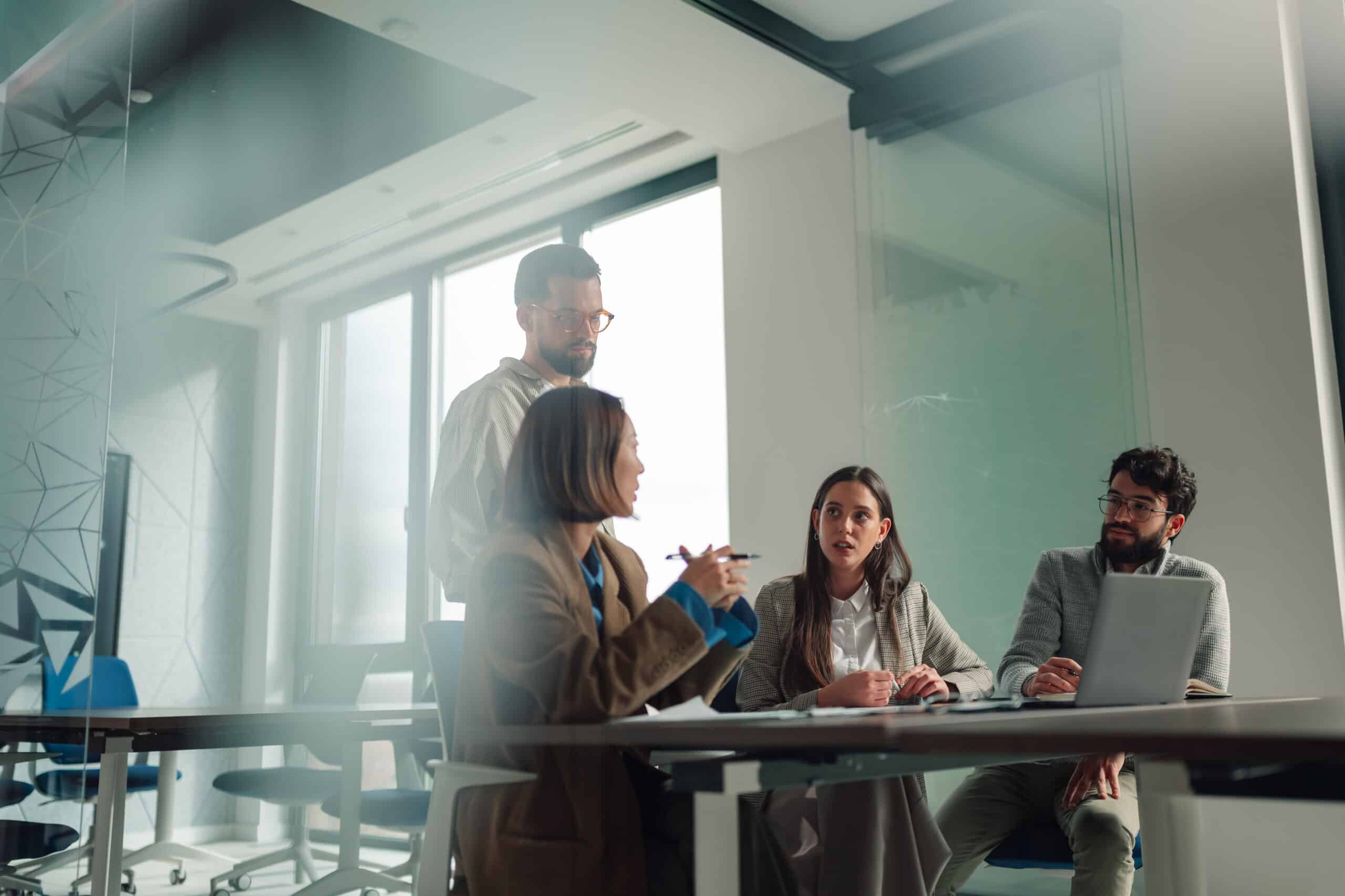 Four people discuss Commercial Lease Dispute Resolution​ in a modern office setting.