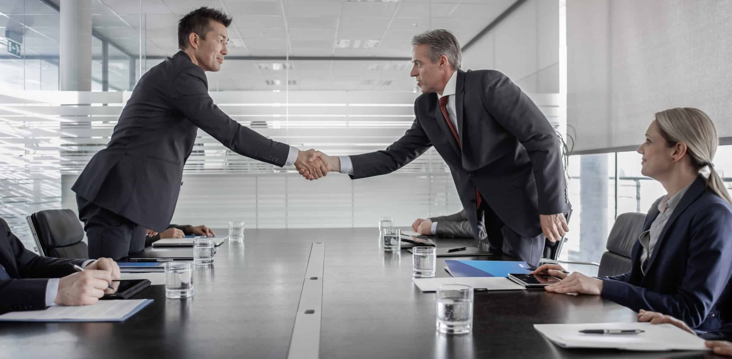 Two businessmen in suits shake hands, finalizing a Commercial Lease Dispute Resolution​.