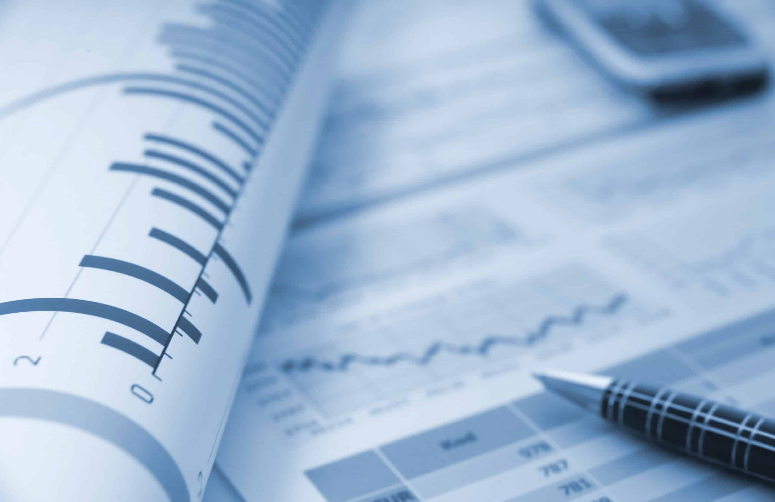 Close-up of financial charts, pen, and documents, representing data analysis and business reports.