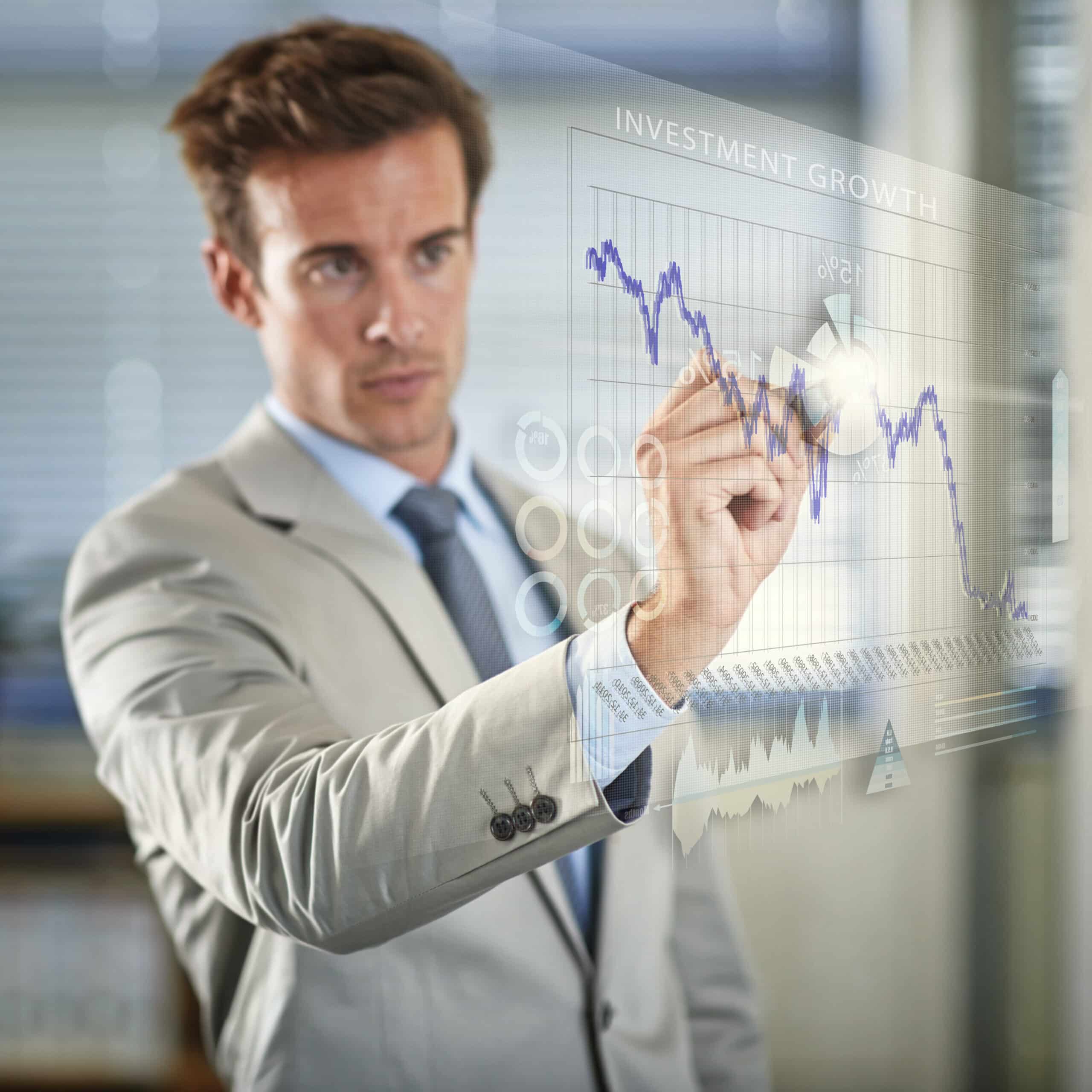 Man in suit analyzing investment growth graph on a transparent digital screen.