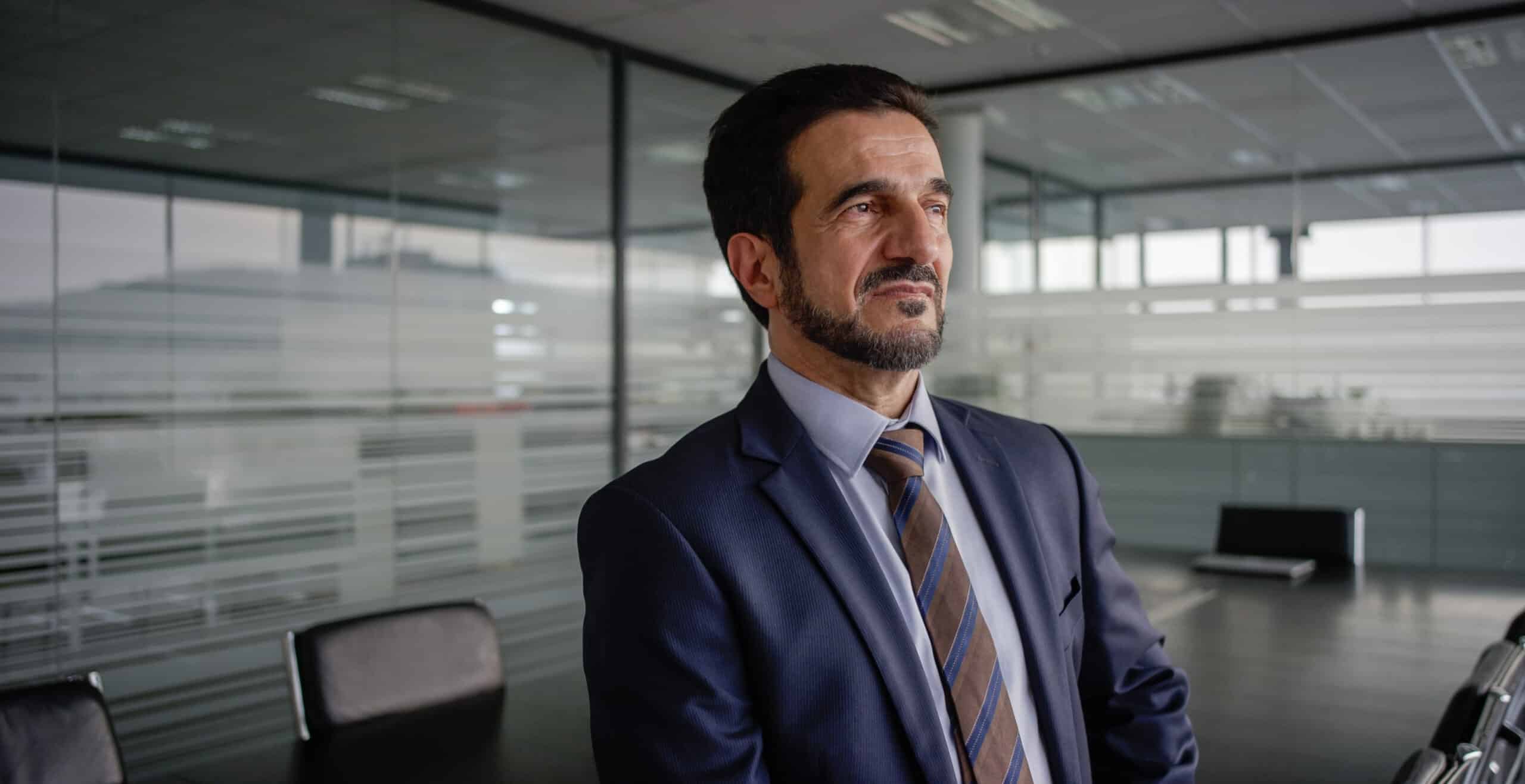 Man in suit stands in modern office, embodying the confidence of IT Governance Consulting.