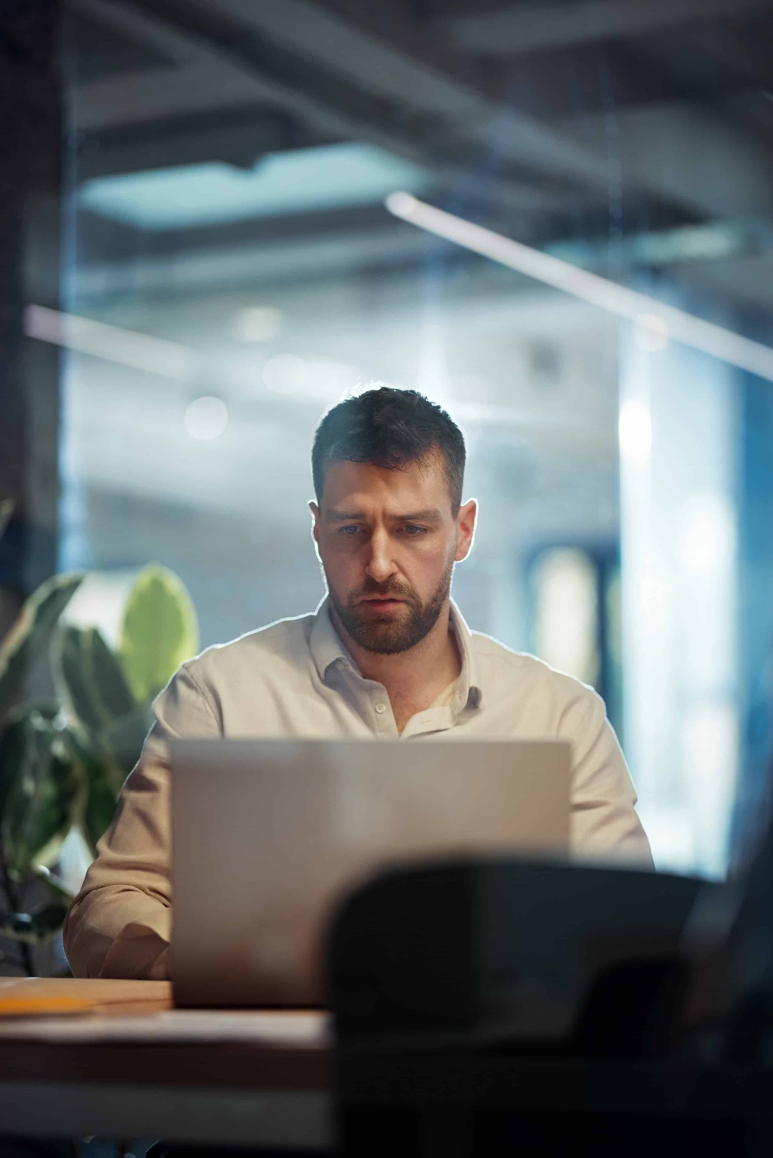 Focused Professional Working on Laptop in Modern Office Environment