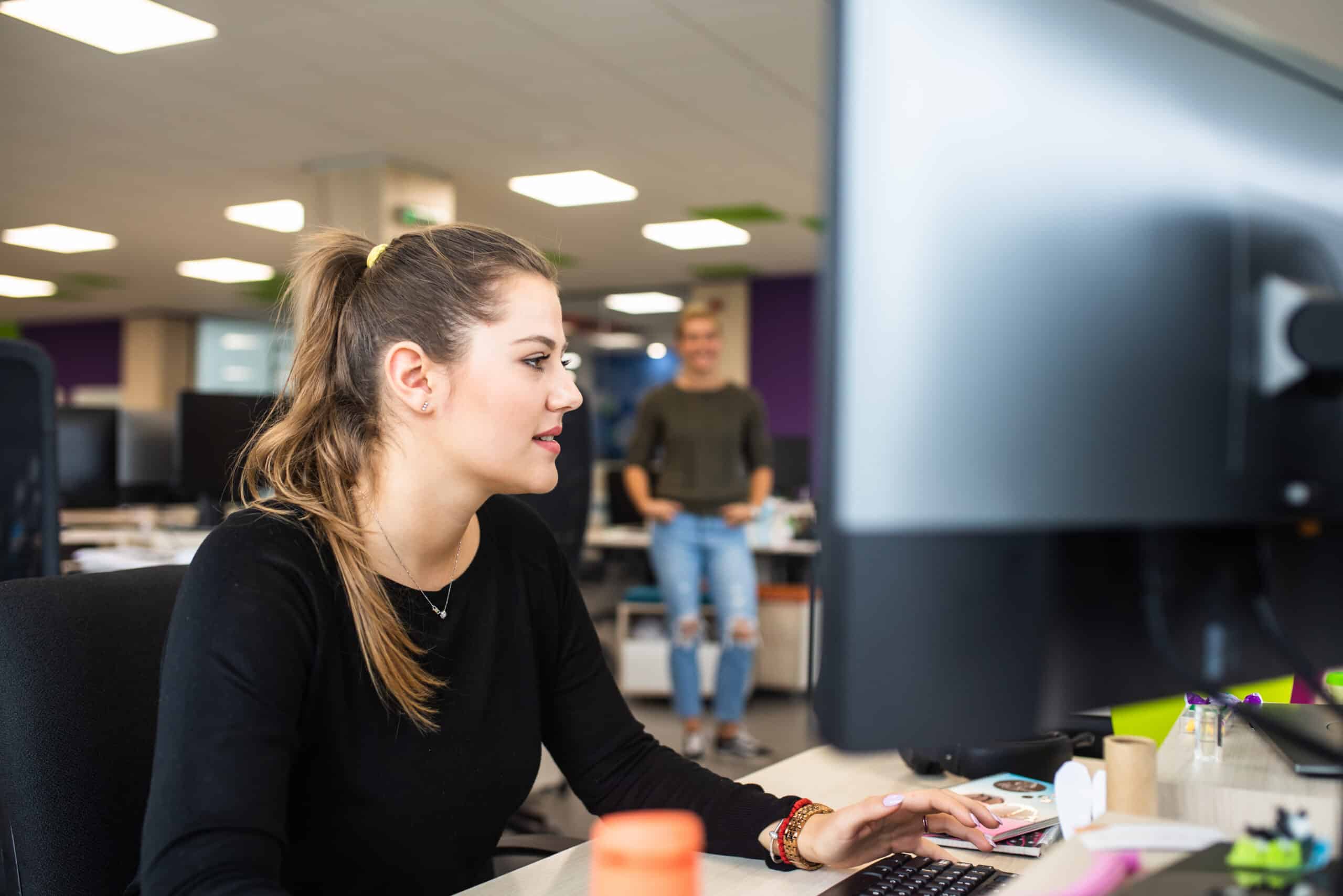 Woman working at a computer in a modern office, specializing in IoT Consulting.