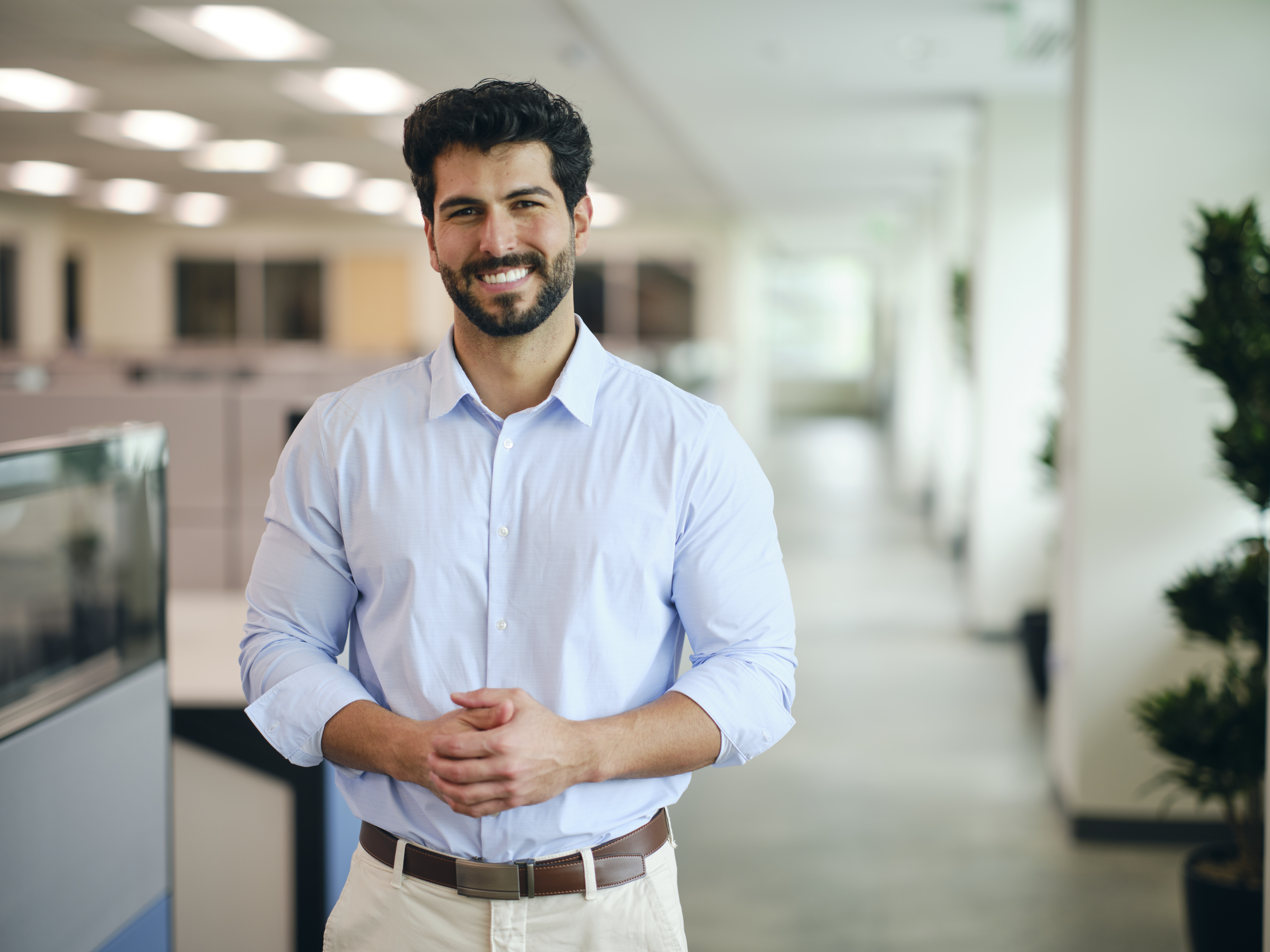 Man with beard smiles in a bright office hallway, reflecting on CRE Tax Management success.