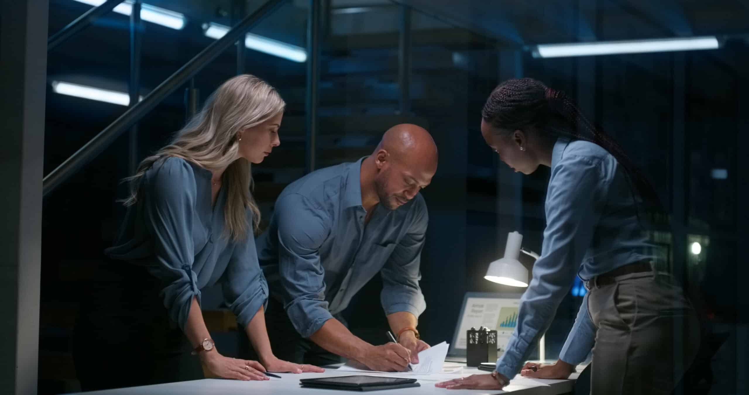 Three IT governance Consultants collaborate at a desk.