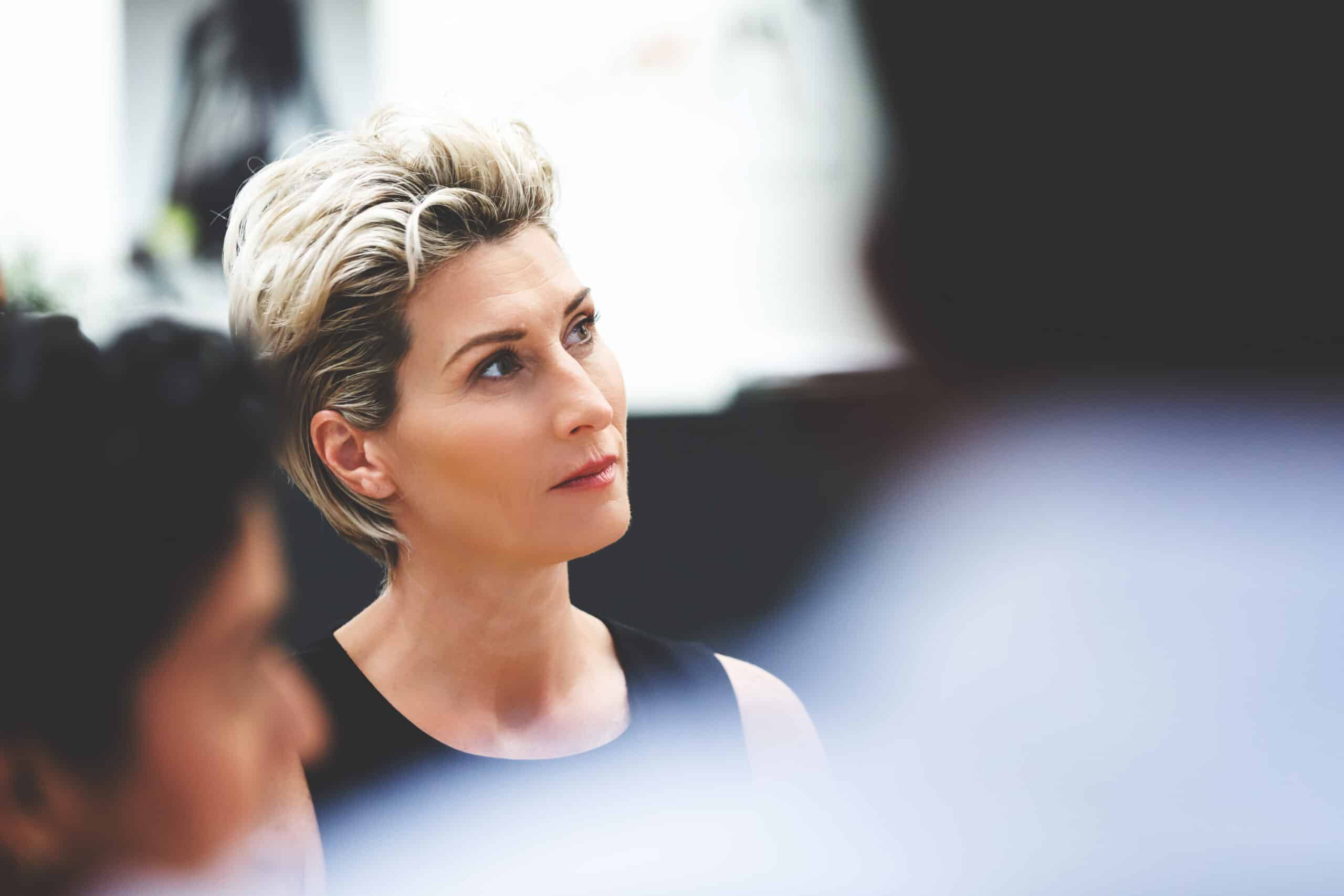 Woman with short blonde hair attentively listening during a Land Use Planning Consulting session.