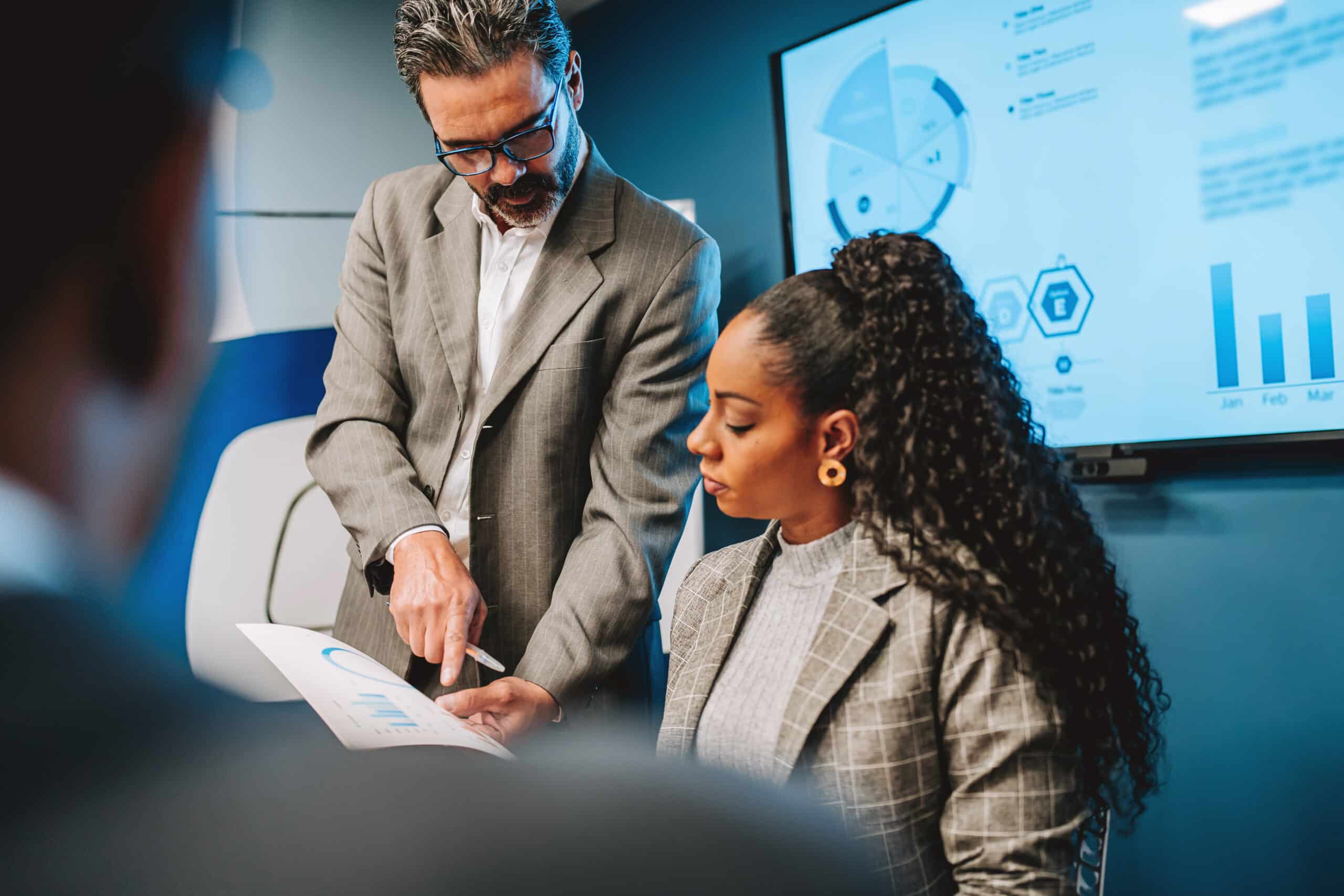 Man and woman review charts in office, discussing Enterprise Systems Transformation strategies.