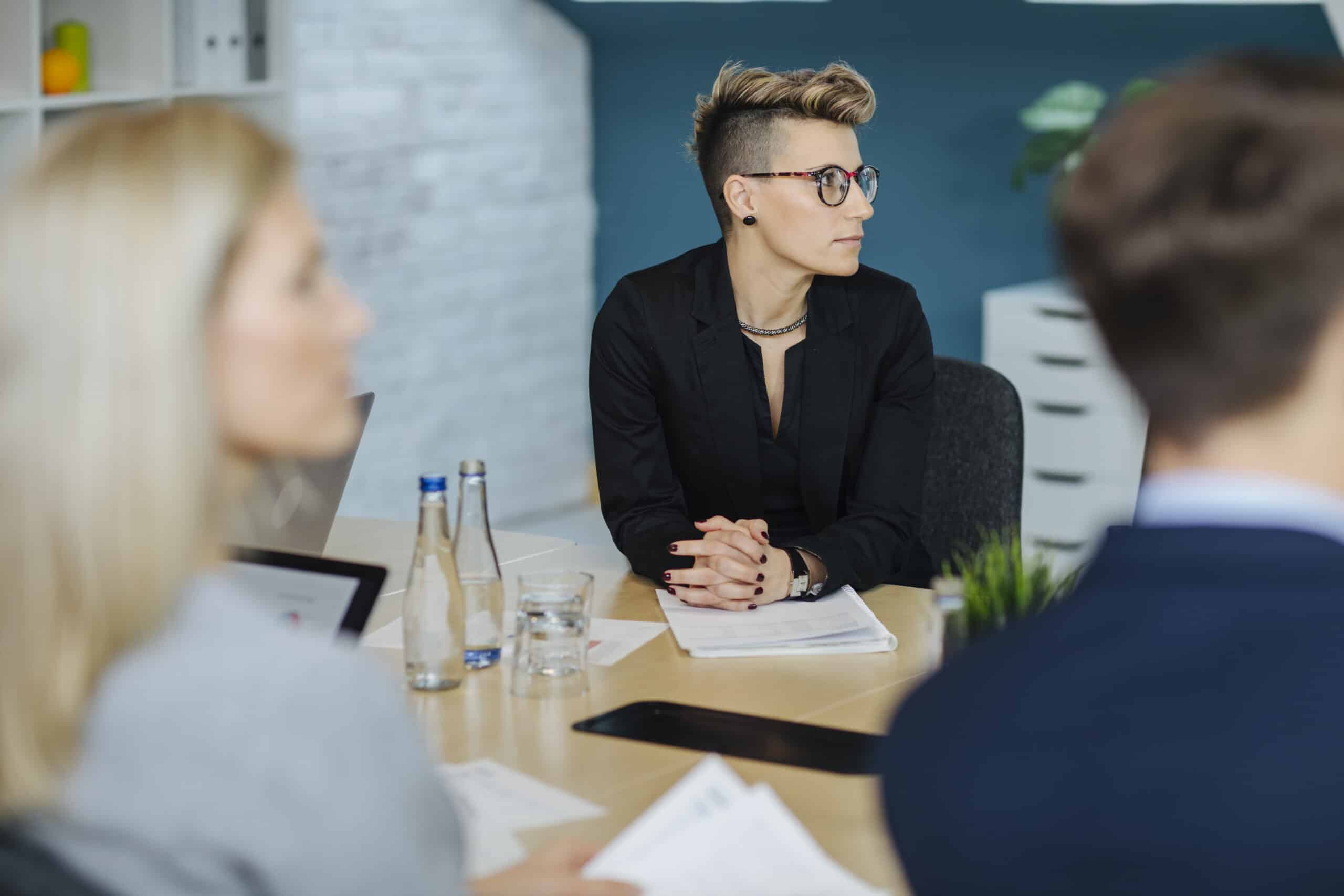 Person with short hair and glasses listens attentively at a CRE Change Management conference table.