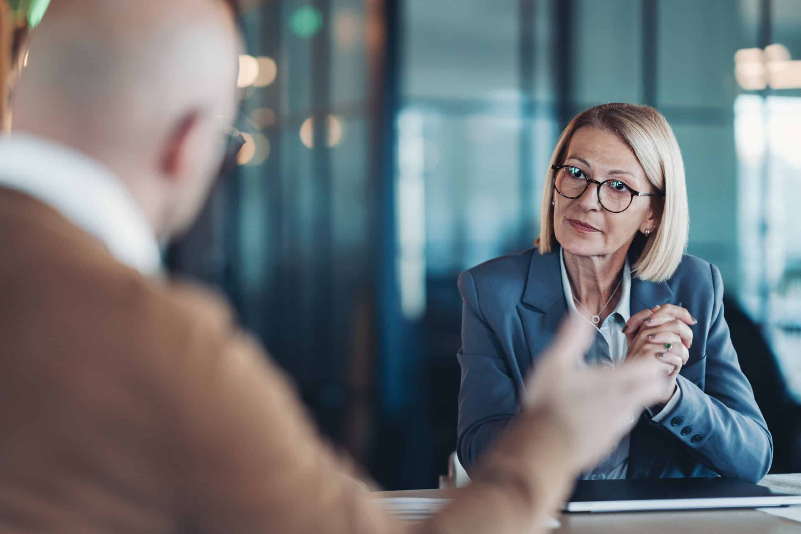 Businesswoman in glasses listens intently during a Leadership Development​ consulting meeting.
