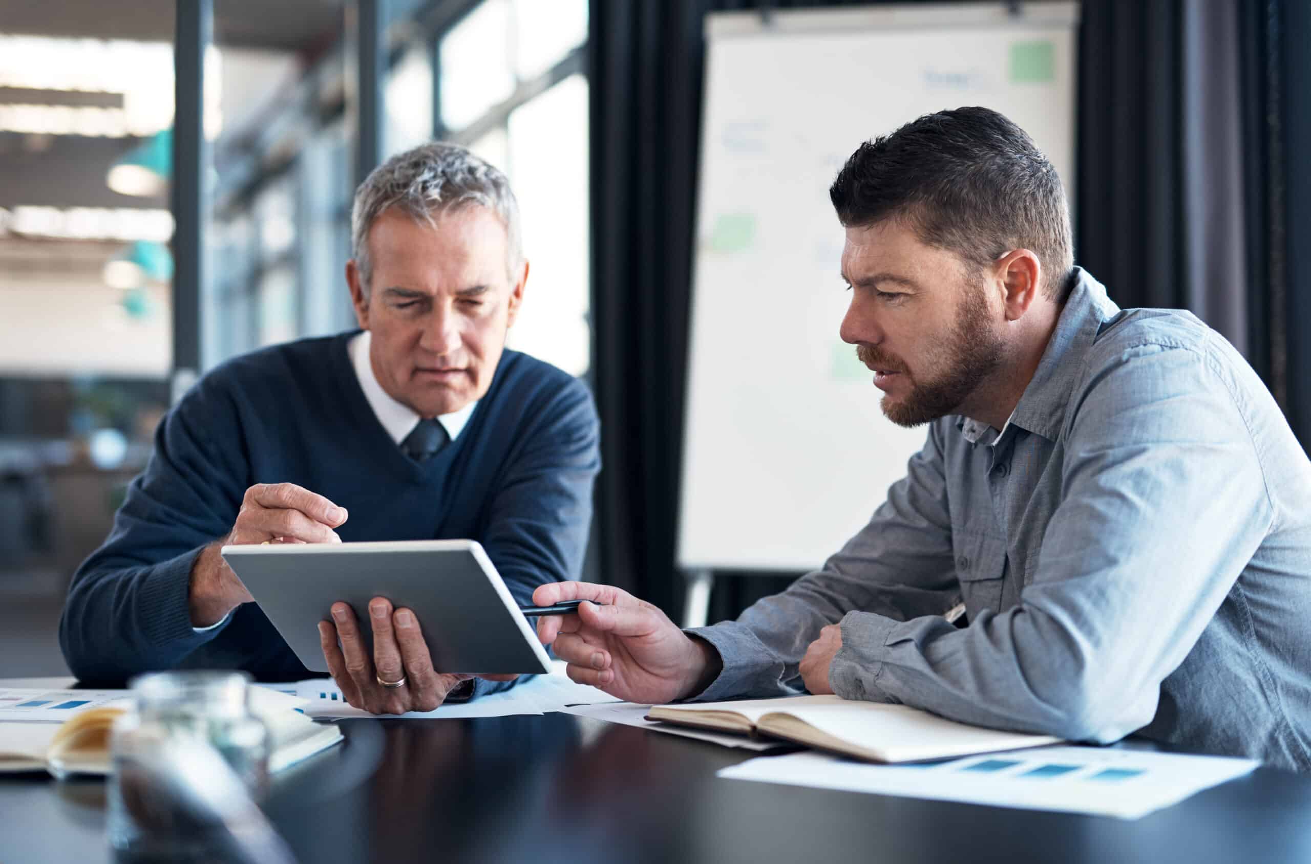 Shot of two businessmen working together on a digital tablet in an office