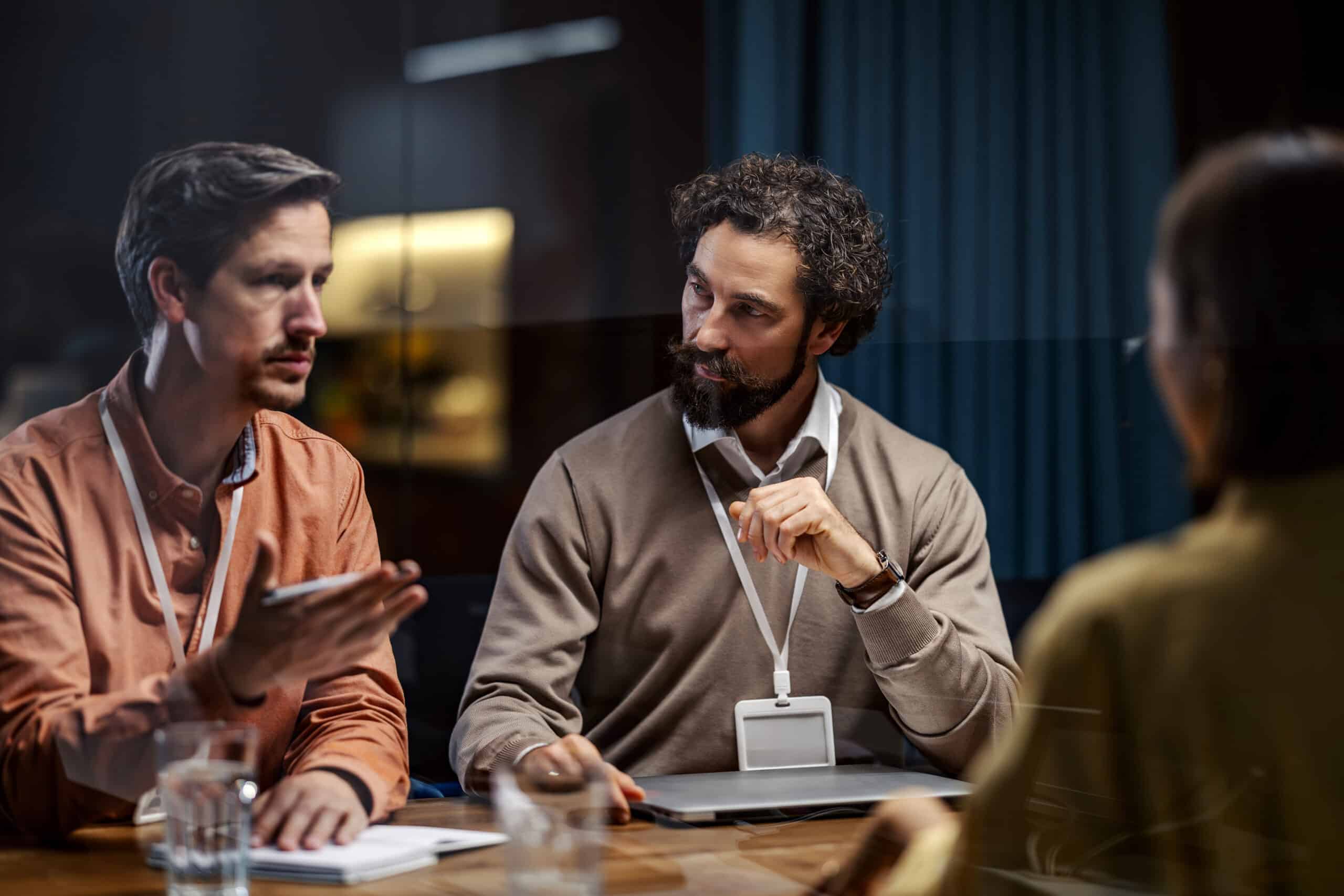 Three people in a meeting discuss Digital Twins while a woman listens across the table.