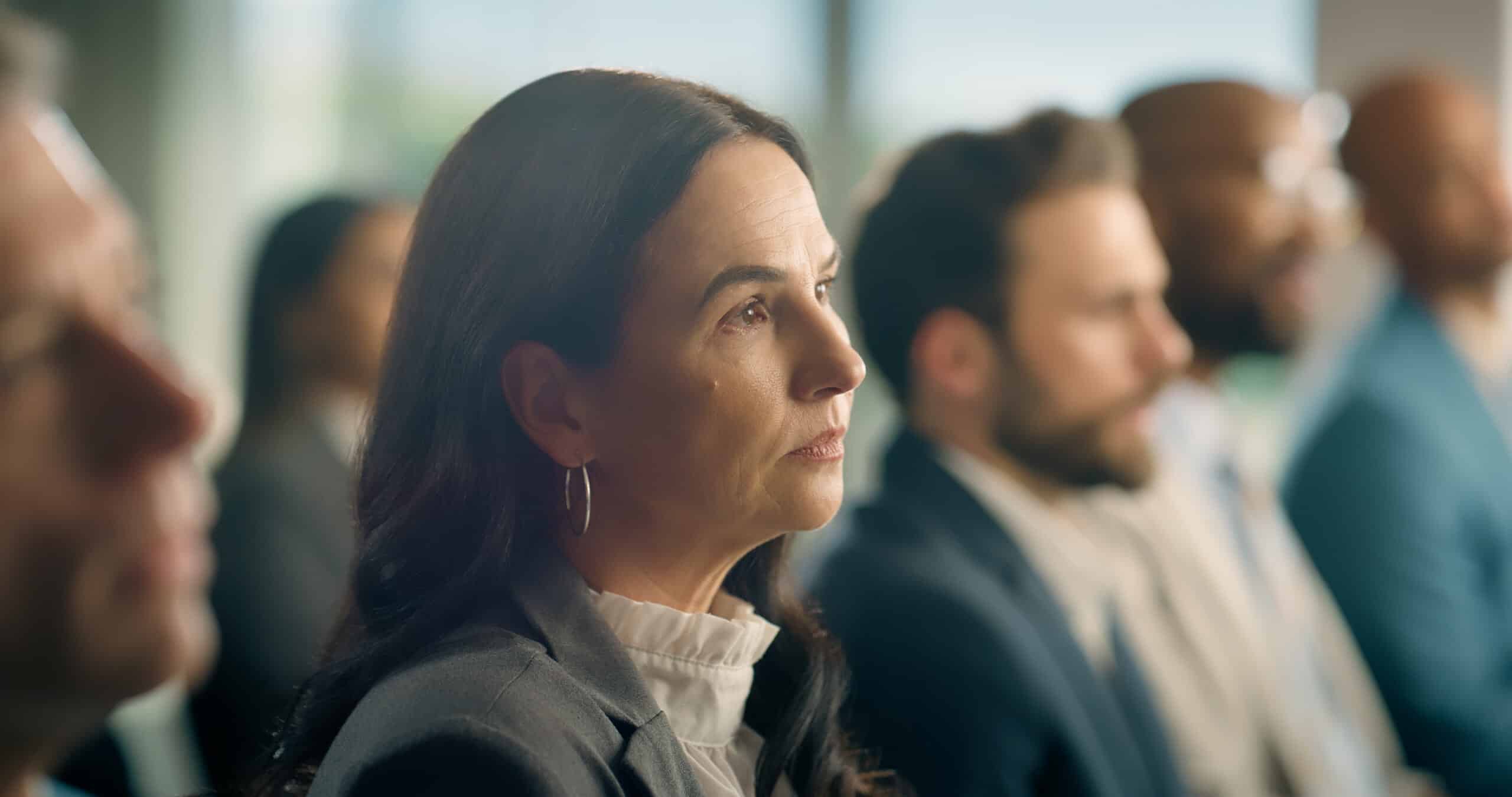 Woman in business attire attentively listening at a Land Use Planning Consulting group discussion.