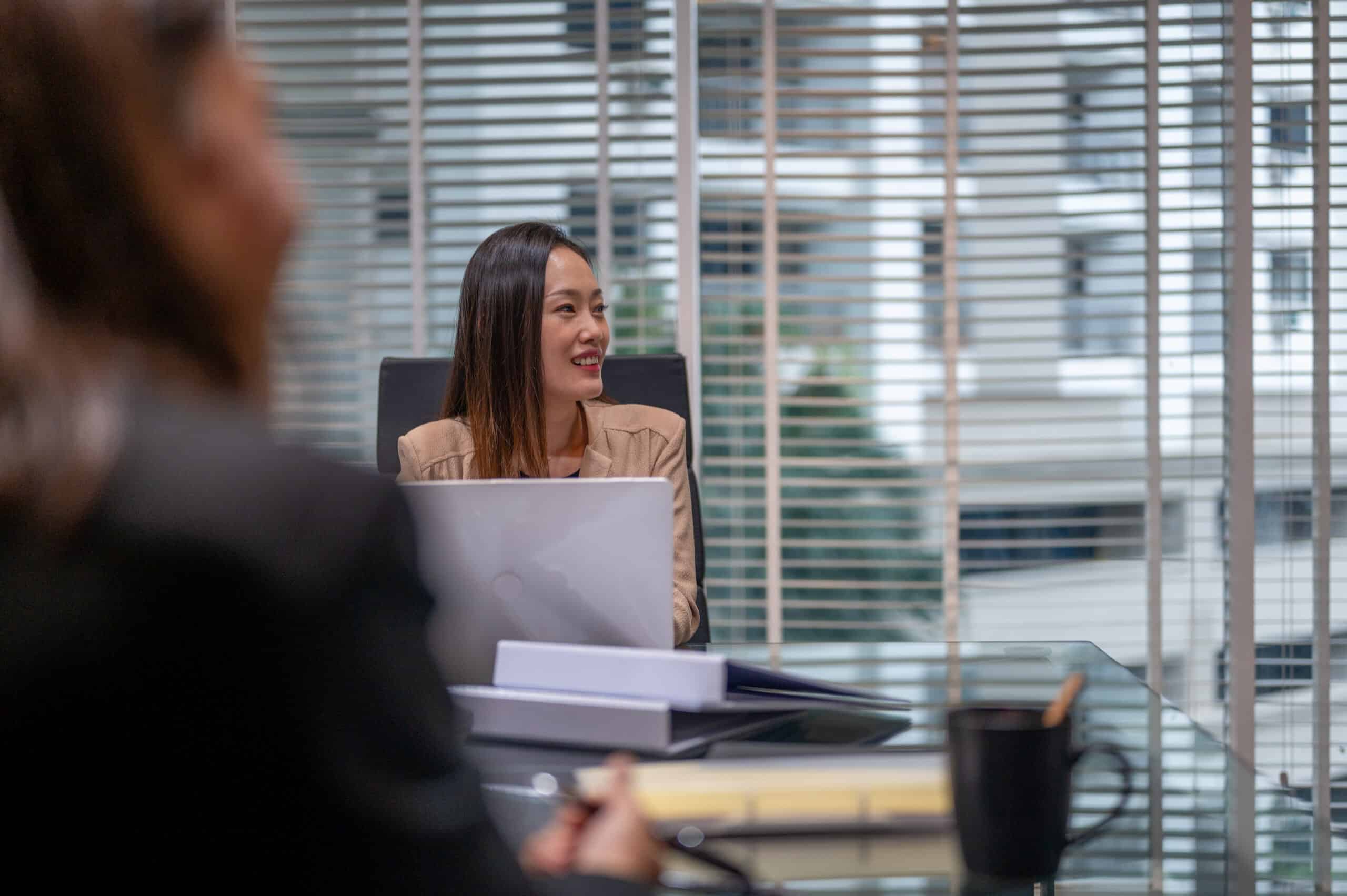 Woman smiling at a conference table, showcasing CRE Workplace Strategy in a modern office.