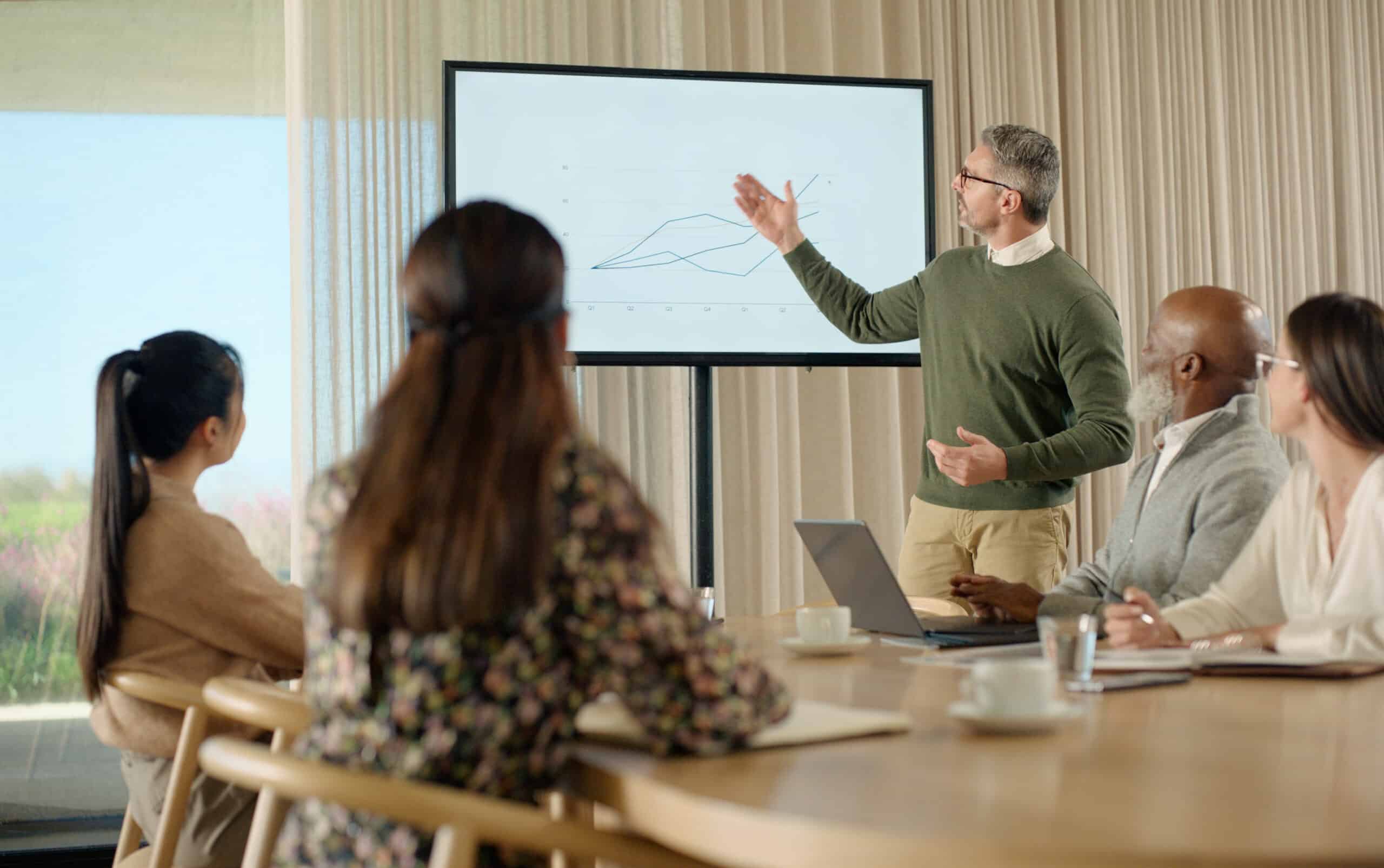 Man presenting a line graph to colleagues during a Land Use Planning Consulting meeting.
