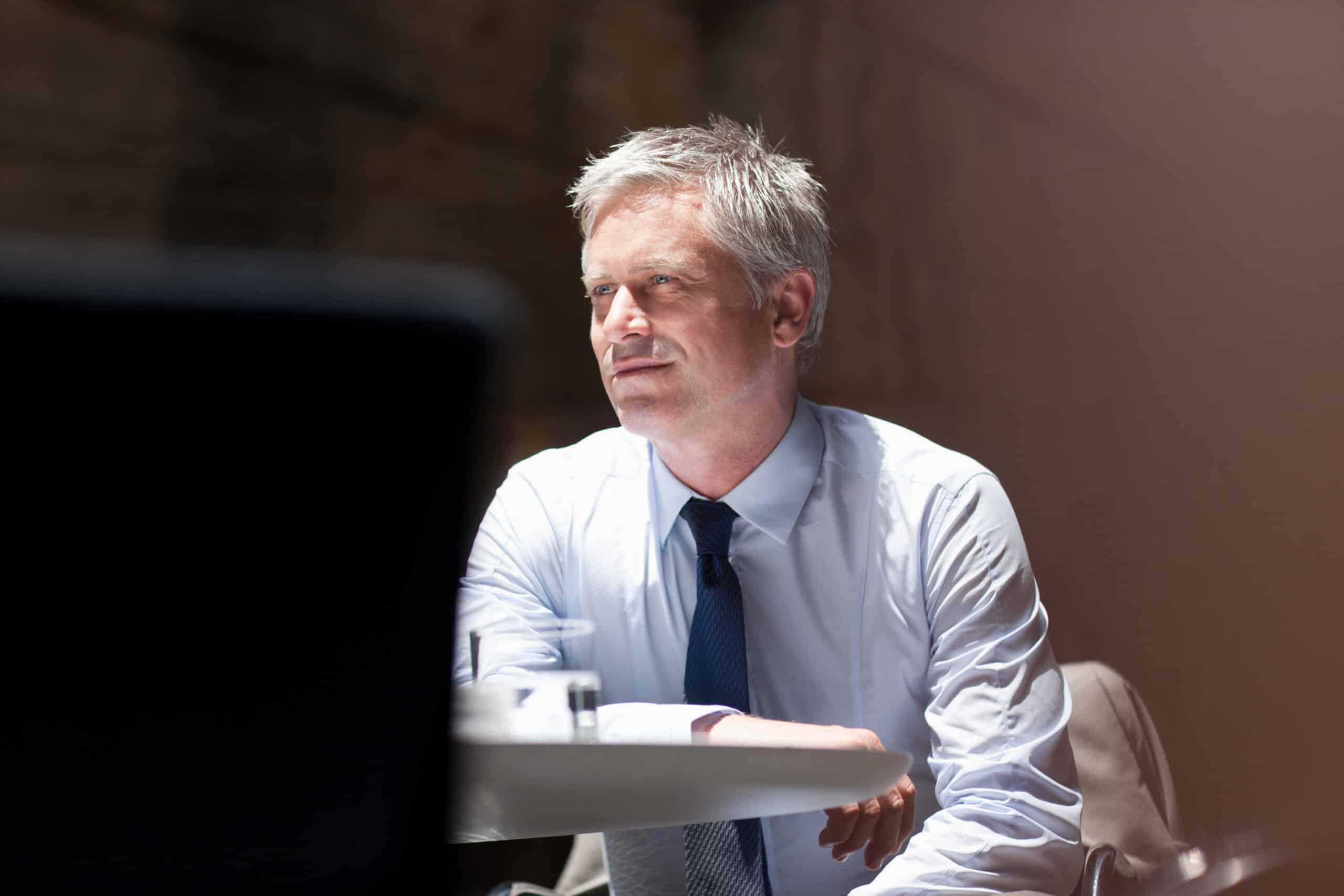 Man in a shirt and tie sits at a table, thoughtfully considering Smart Building solutions.