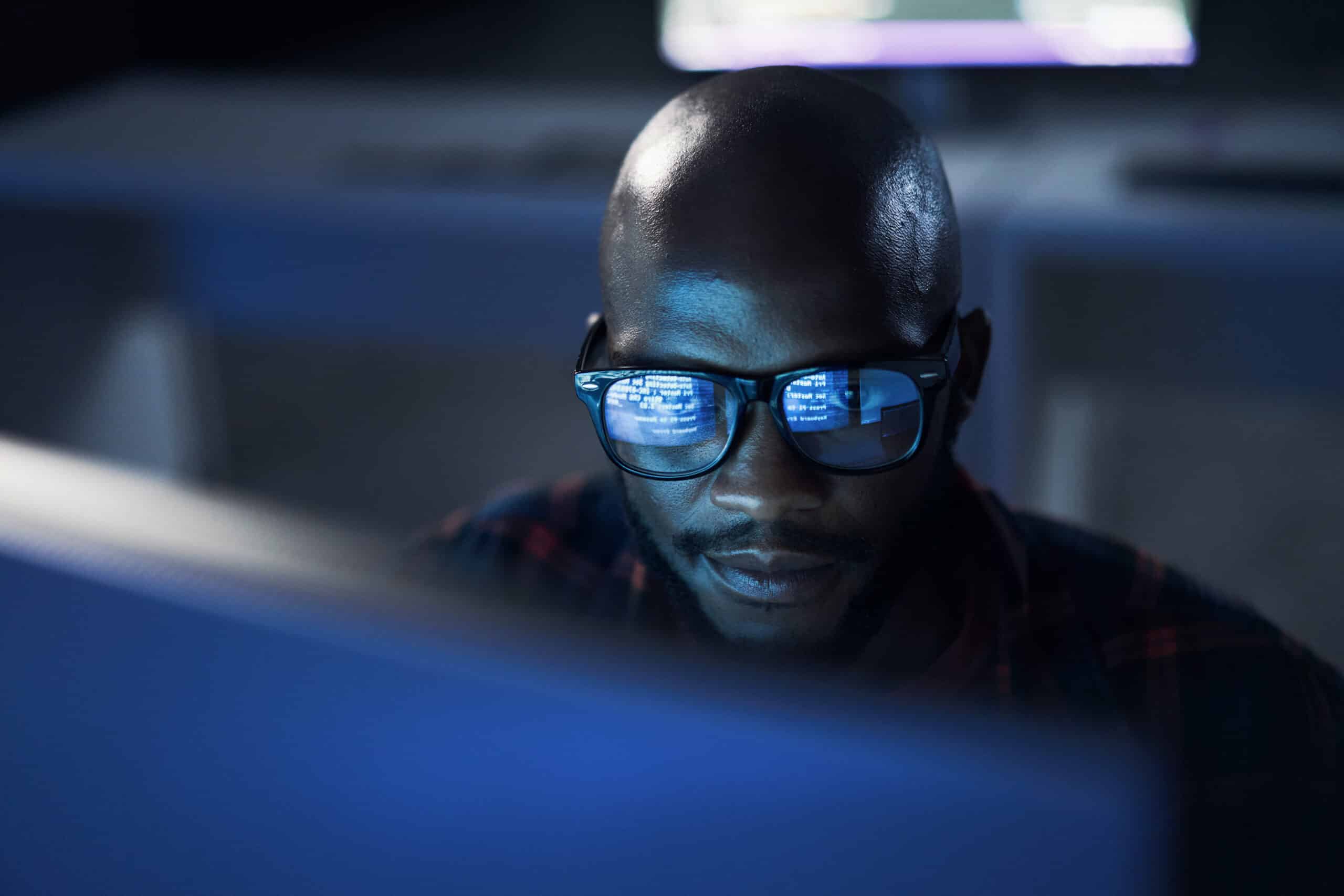Man wearing glasses looks at a computer screen, reflecting Proptech Consulting expertise.