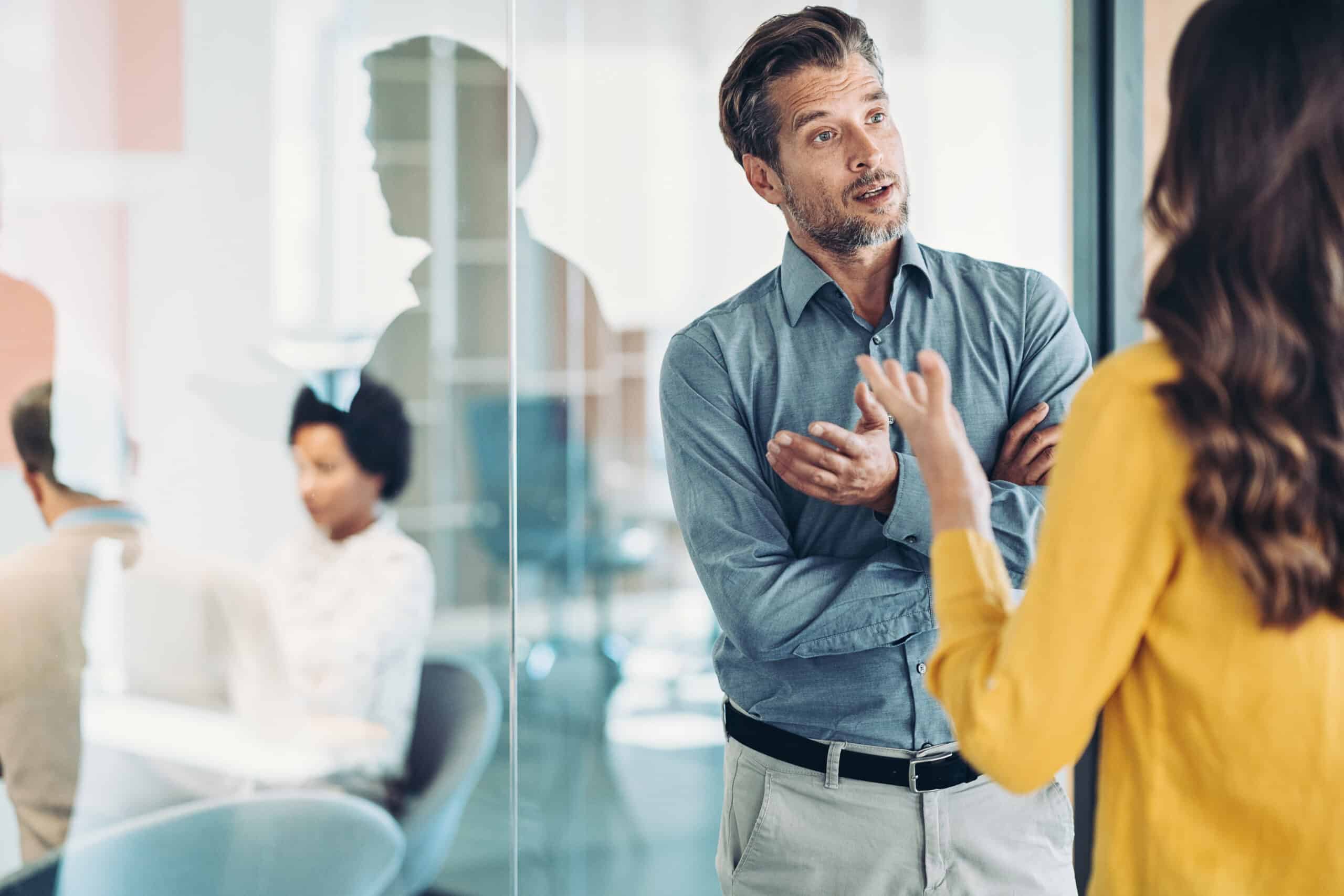 Man and woman discuss Enterprise Application Integration in a busy office setting.