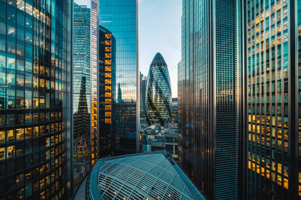 Cityscape with modern skyscrapers and the distinctive Gherkin building in London at dusk.
