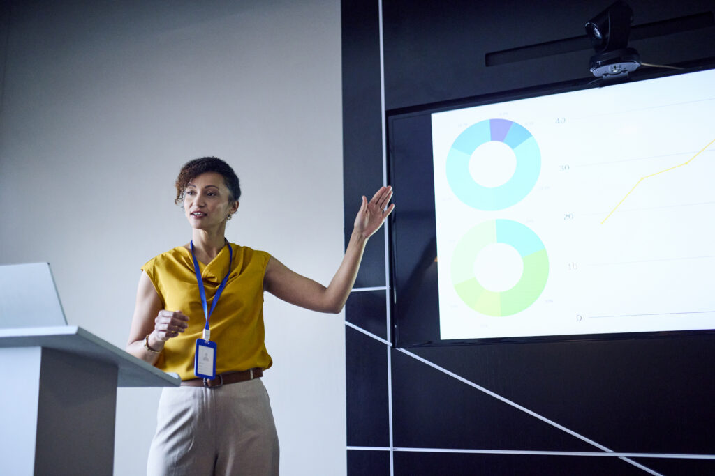 Professional woman presenting data on a screen representing cost reduction consulting