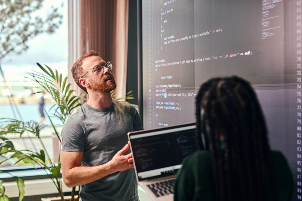 Two young adult programmers discussing code representing devops consulting services