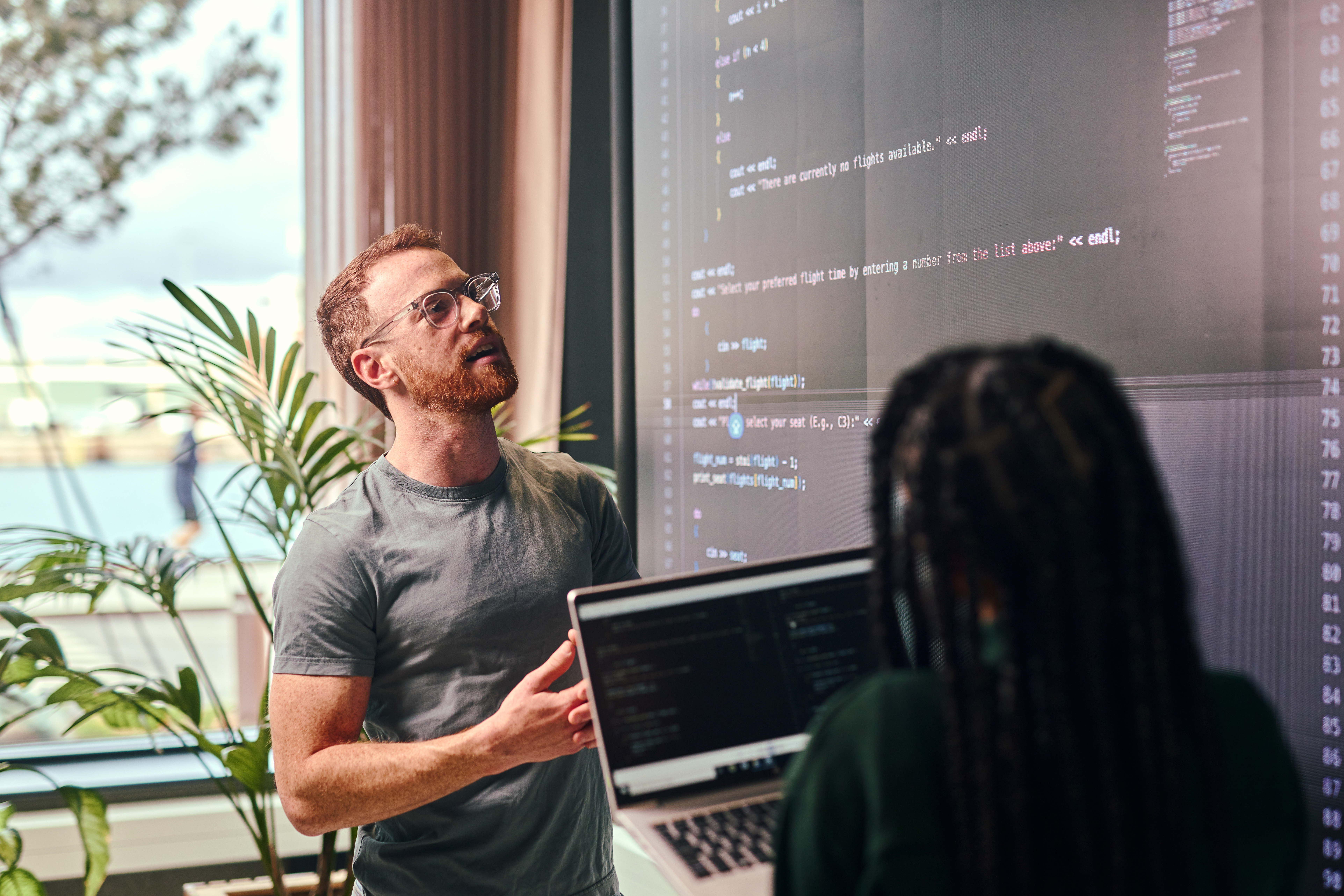 Two young adult programmers discussing code representing devops consulting services