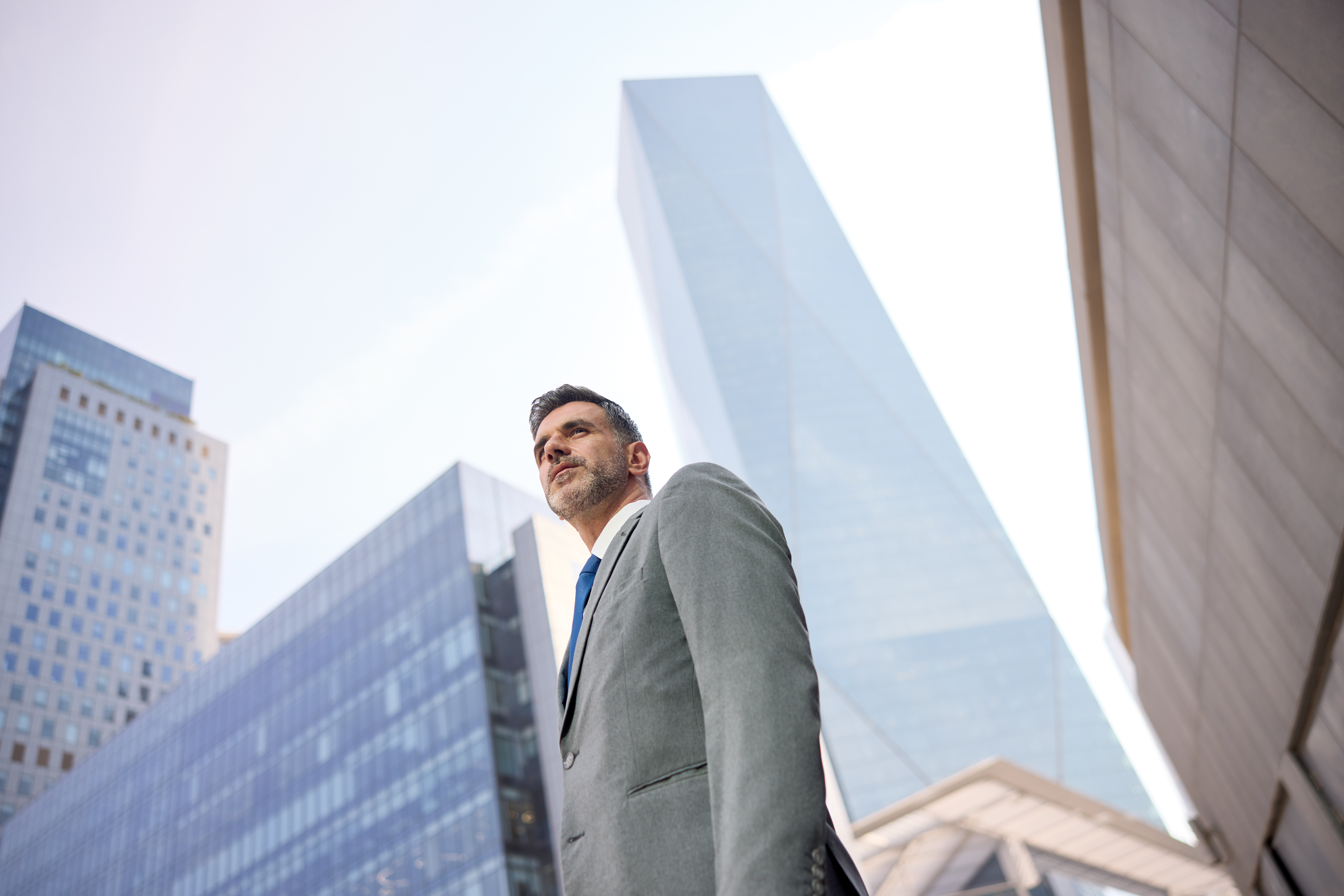 Man in a suit stands outside tall office buildings, reflecting global mobility consulting expertise.