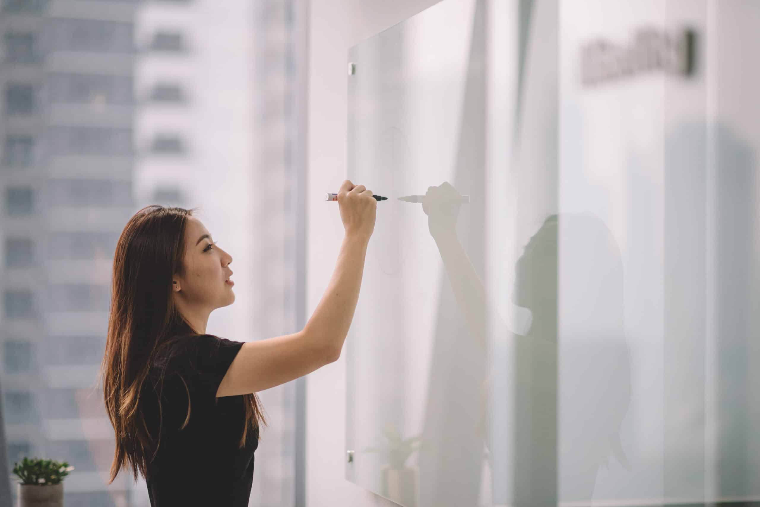 Businesswoman writing on white board representing organization design consulting